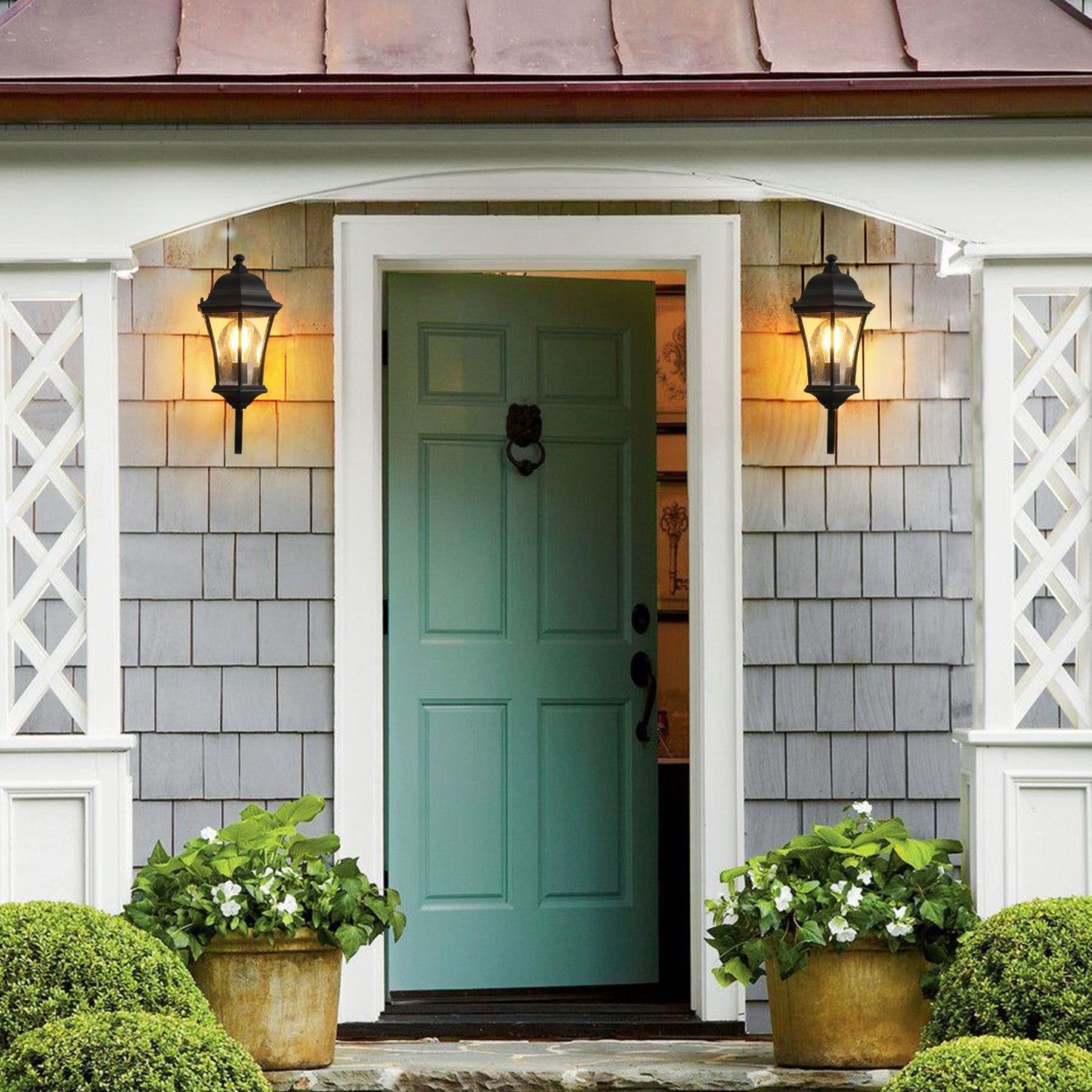 Black cast iron outdoor lantern with glass panels mounted beside teal front door