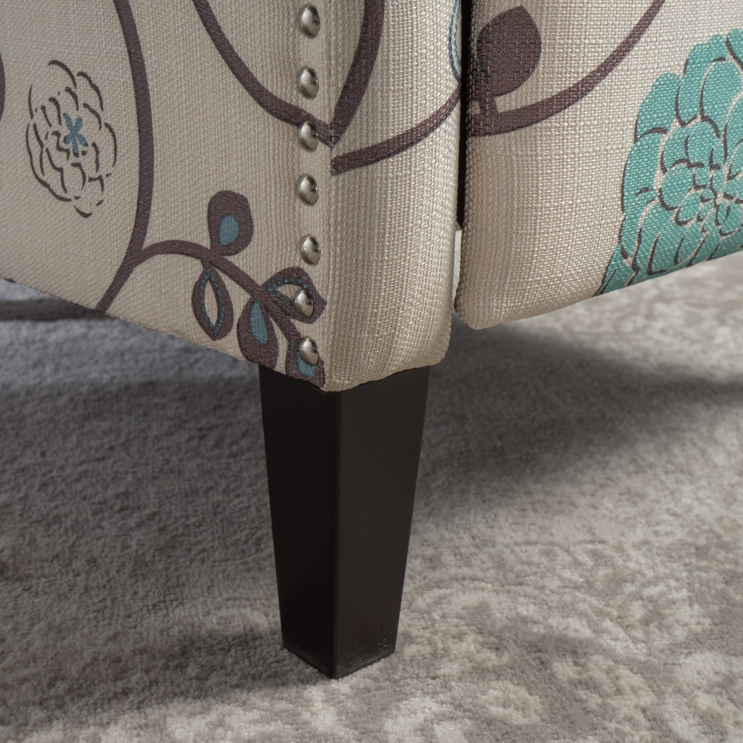 Beige upholstered armchair with floral pattern and dark wood legs