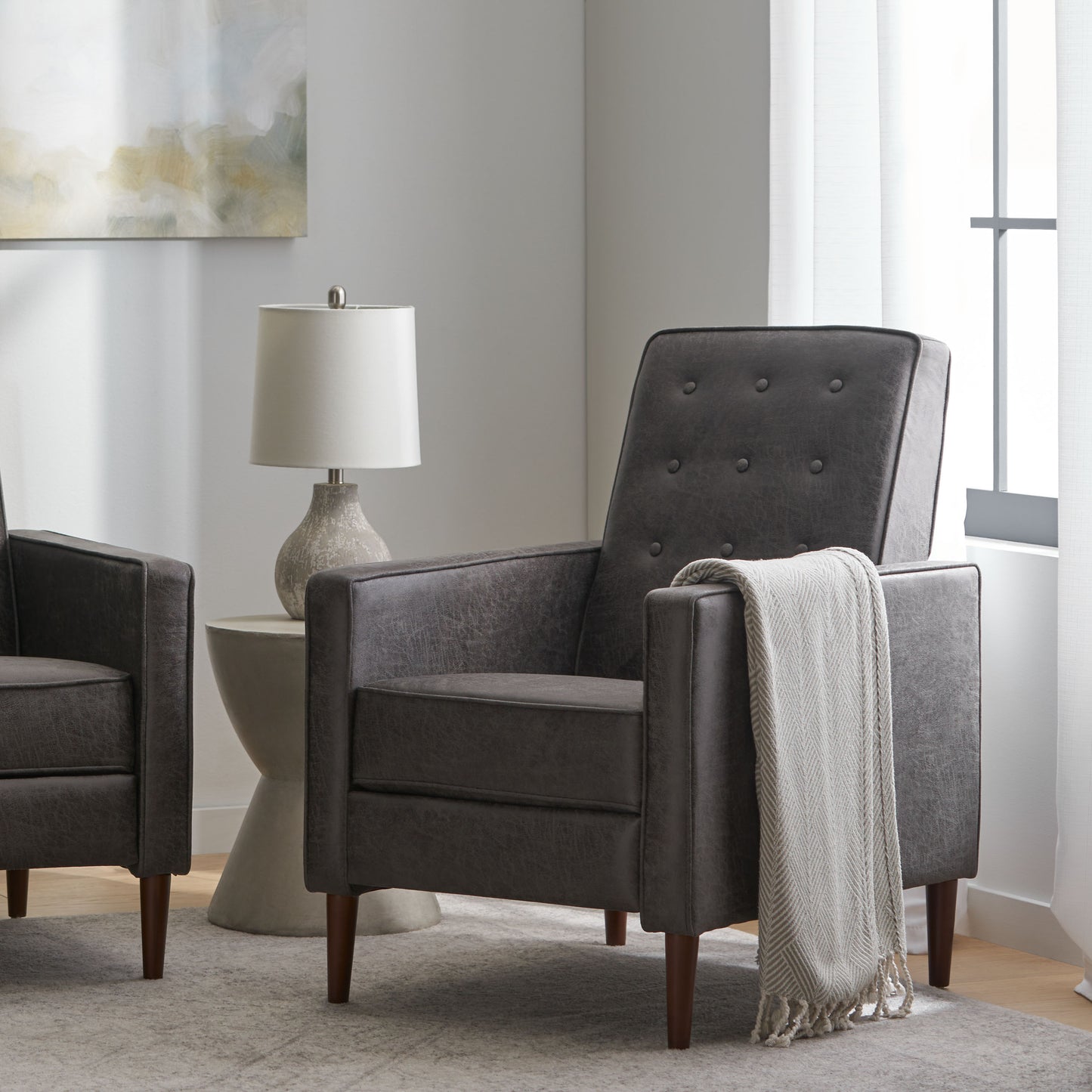 Dark grey faux leather armchair with tufted back and wooden legs