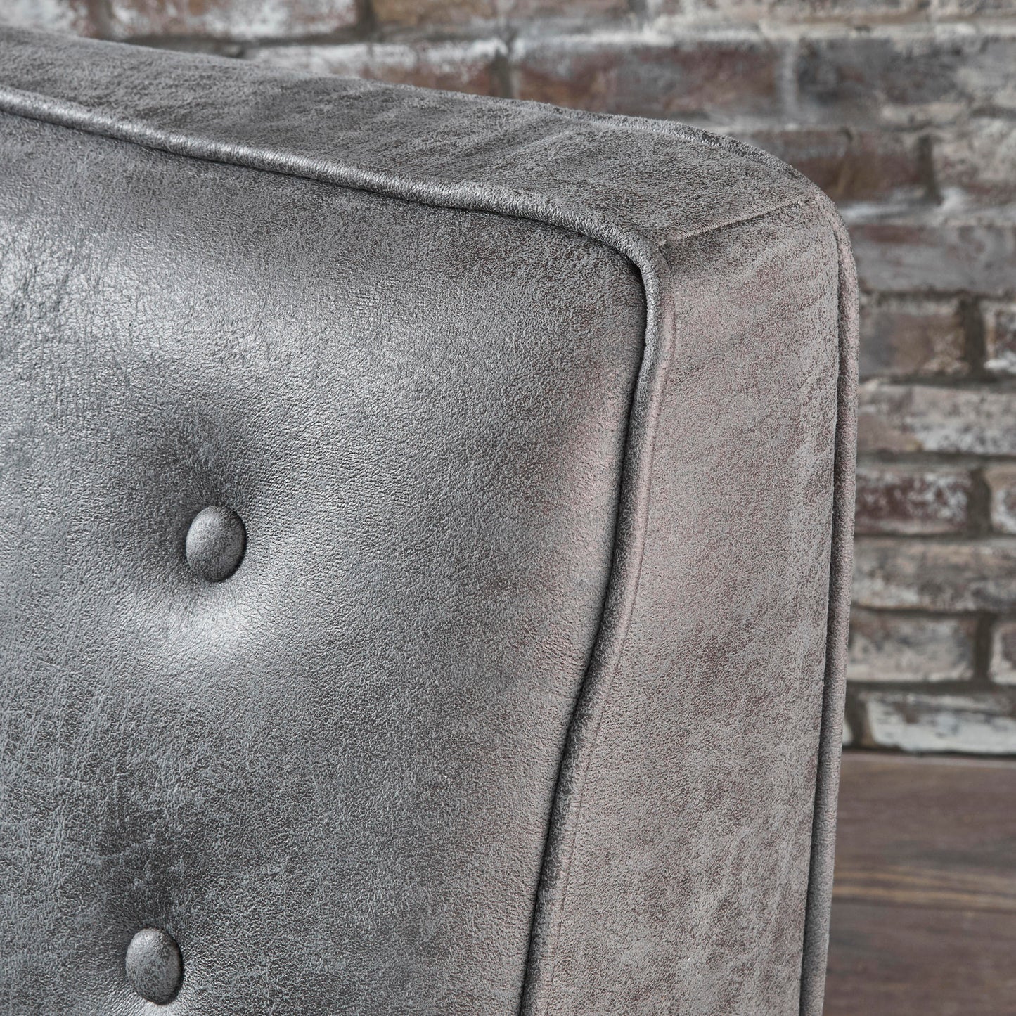 Closeup of charcoal tufted armchair upholstery with a distressed finish