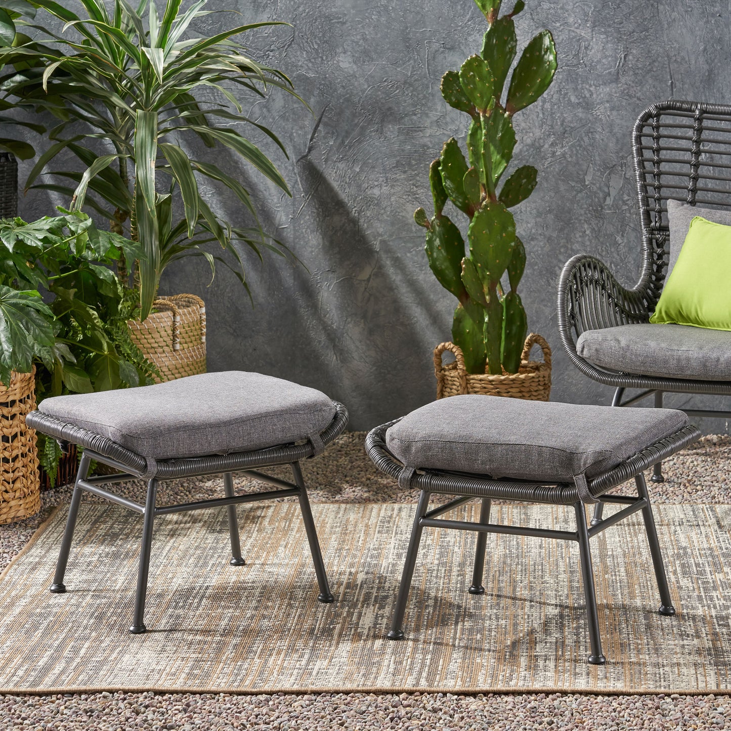 Two grey wovenstyle outdoor ottomans with comfortable seat cushions on a patterned rug
