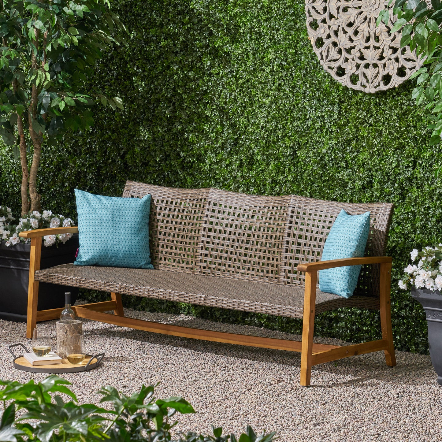Woven wicker outdoor bench with wooden frame and teal patterned cushions perfect for garden seating