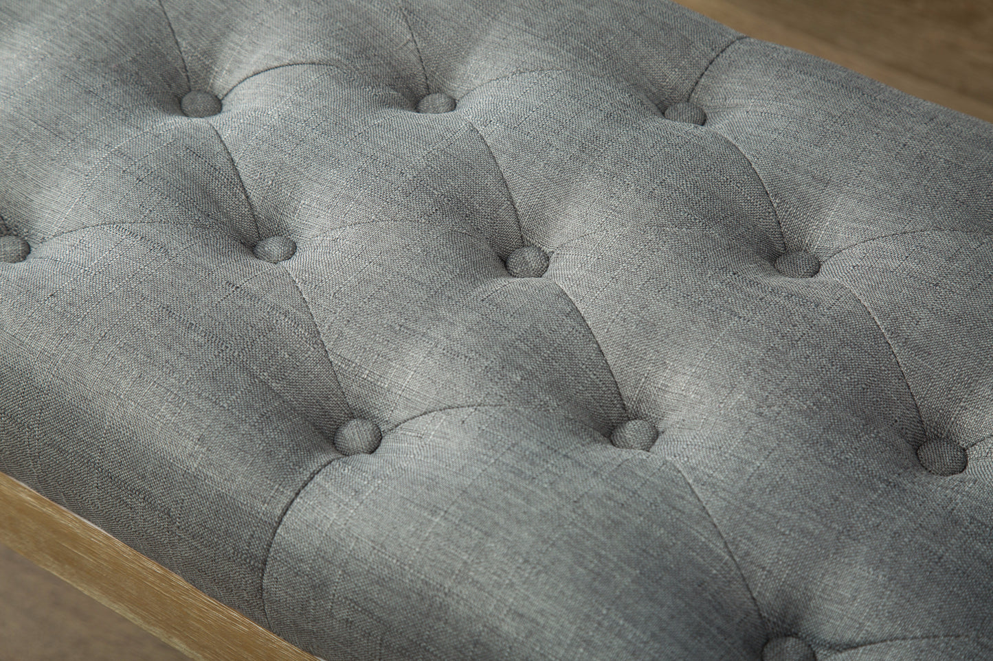 Gray tufted fabric ottoman with natural wood frame detail