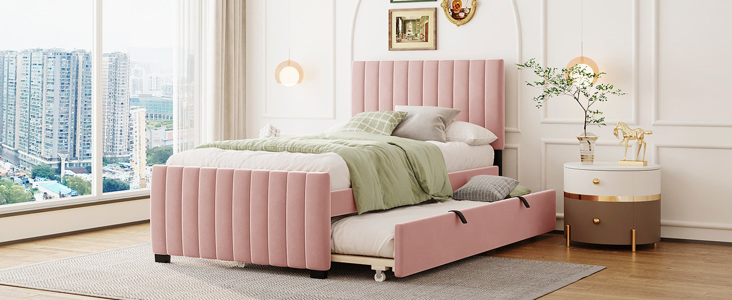 Pink upholstered twin bed with a pullout trundle featuring vertical channel tufting on the headboard and frame