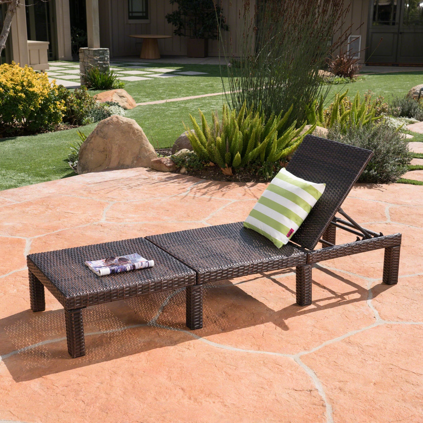 Brown wicker chaise lounge with adjustable back and green striped pillow for outdoor relaxation