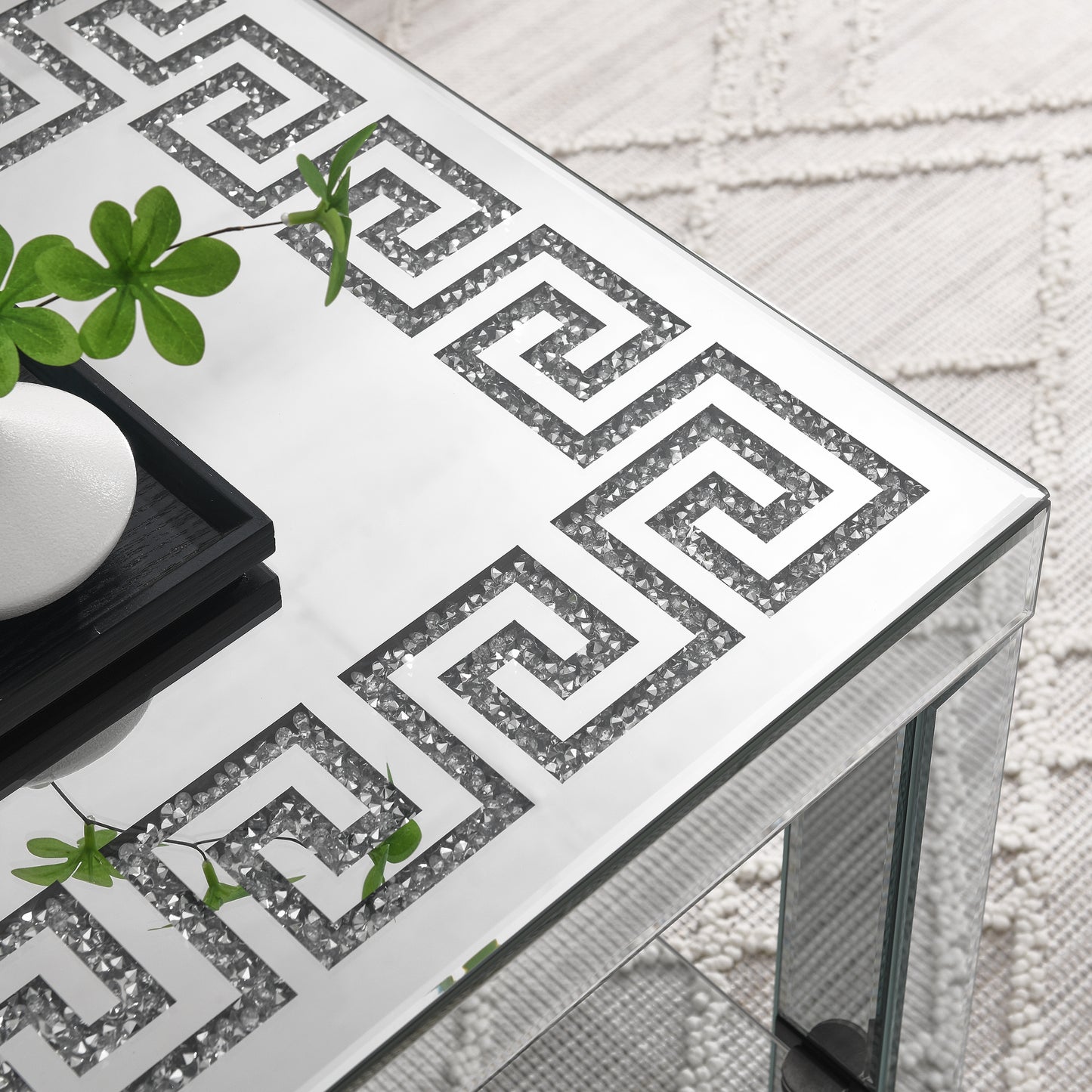 Mirrored coffee table with geometric Greek key crystal inlay and green plant accent