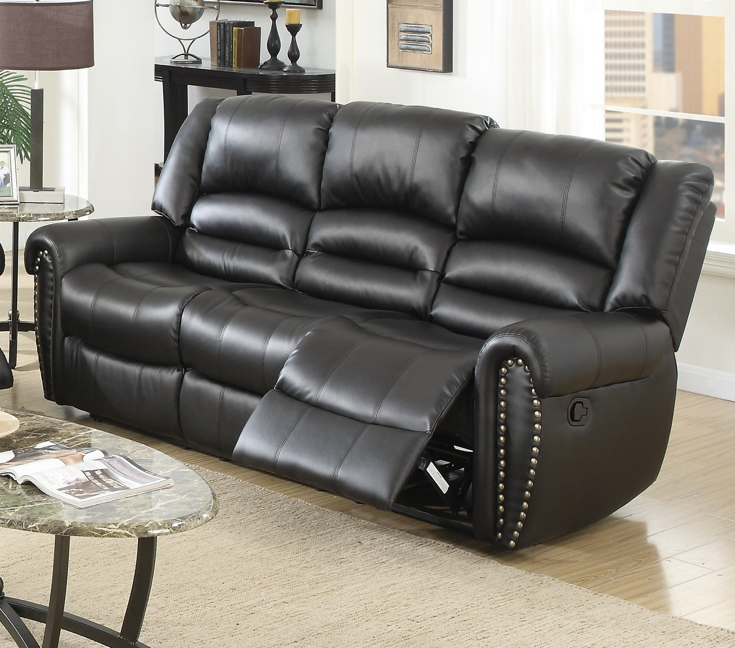 Black leather reclining sofa with plush cushioning and decorative nailhead trim for a modern living room