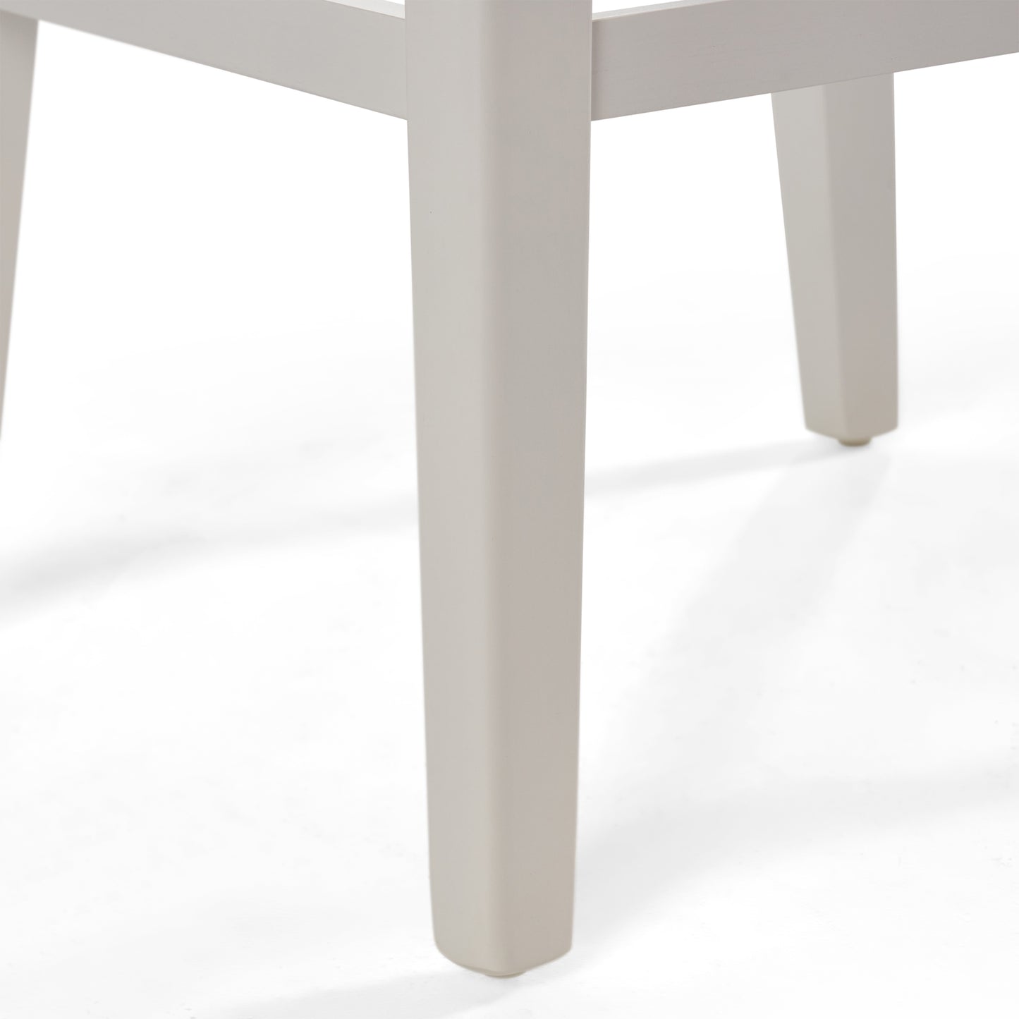 Close up of a modern beige dining chair leg showing square profile and small foot