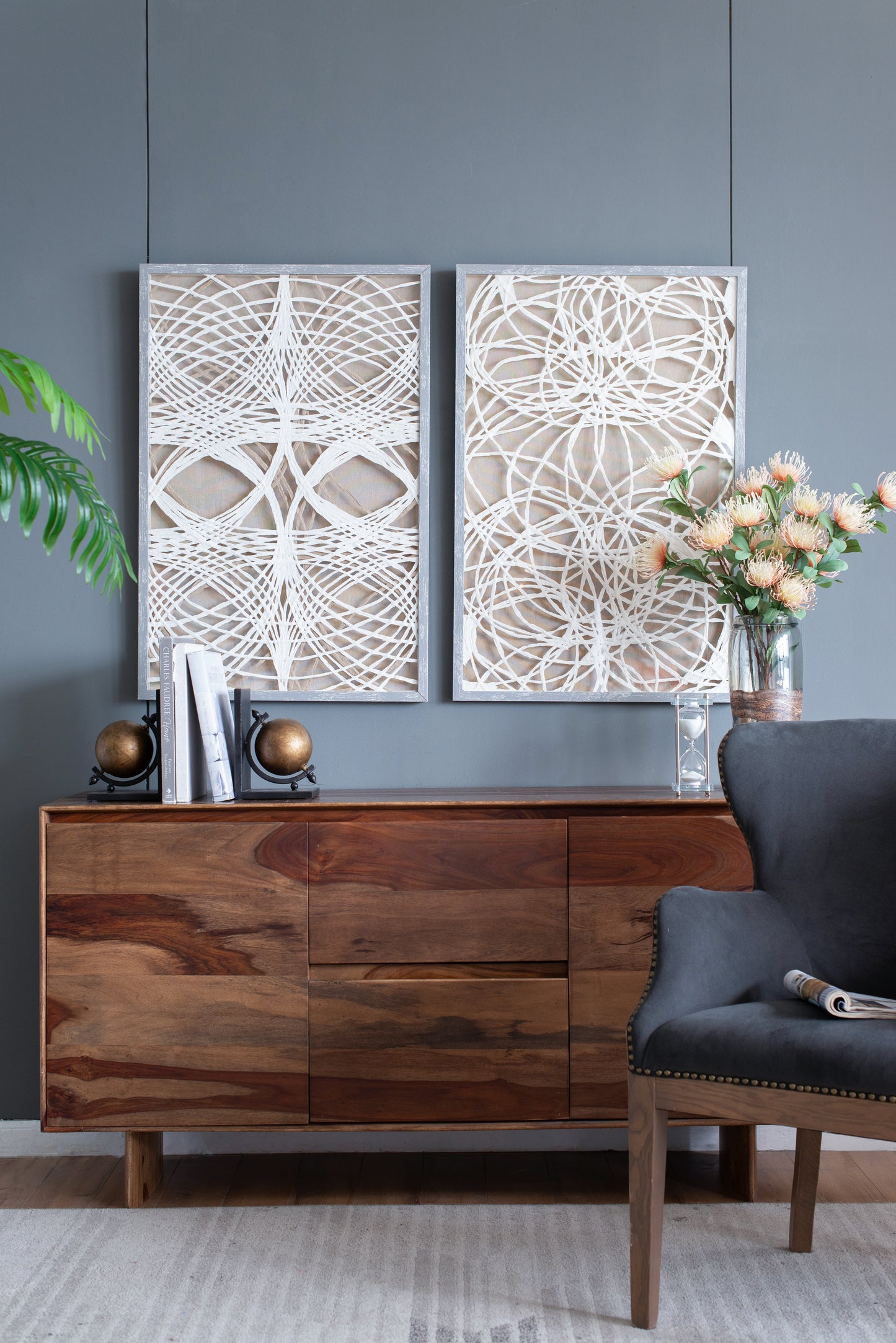Wooden sideboard with brass globe bookends and framed abstract art