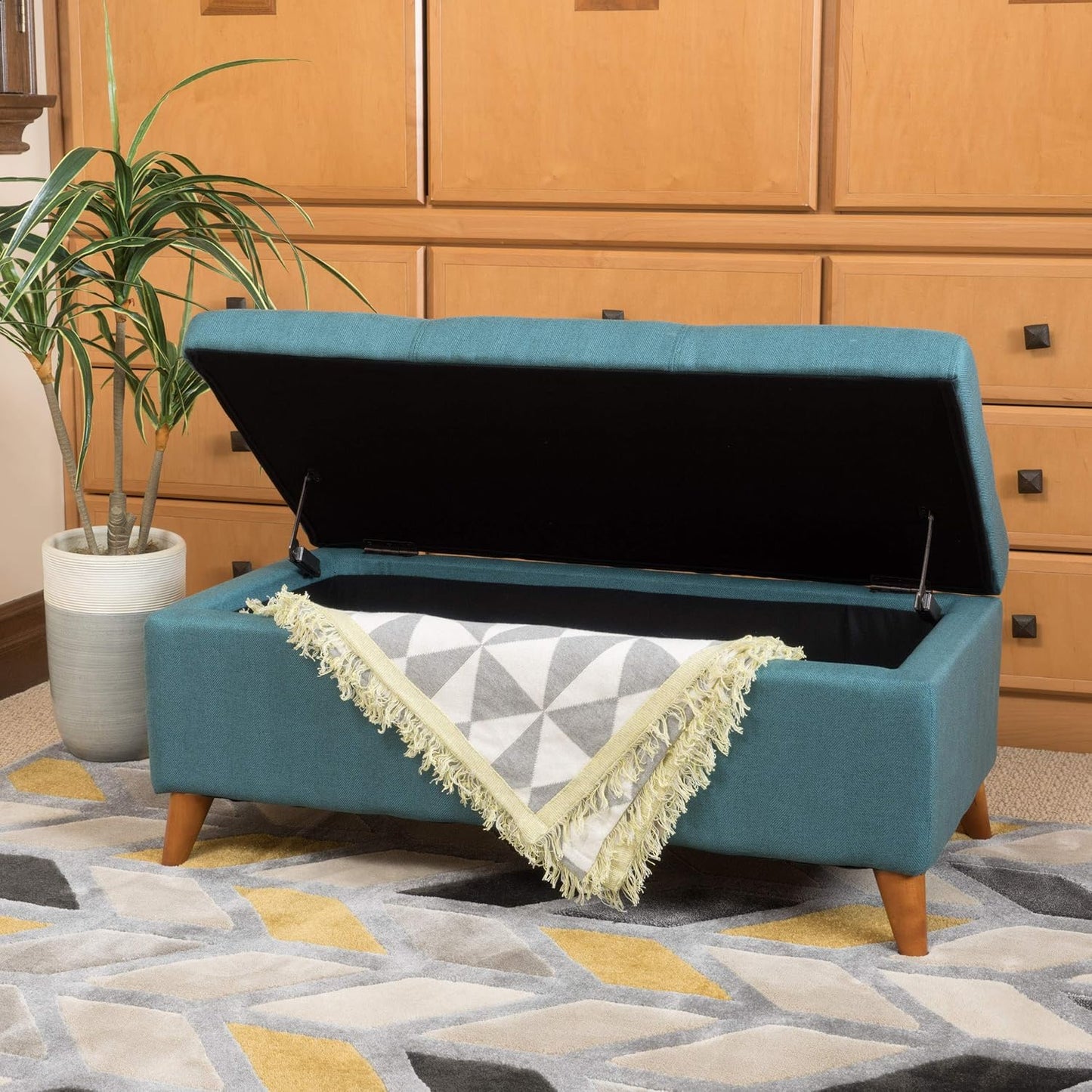 Teal fabric storage ottoman with open lid revealing blanket storage