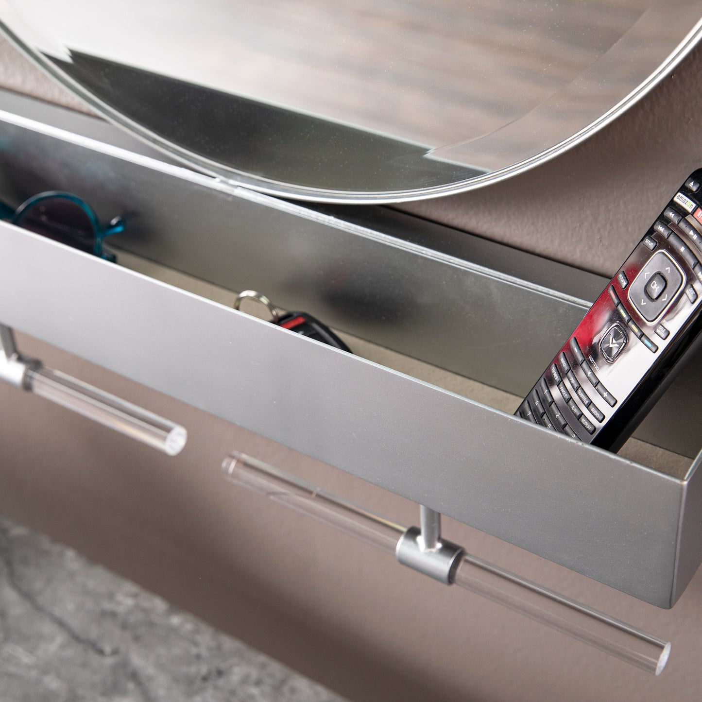 Sleek metal entryway shelf holding keys sunglasses and a TV remote for organized living