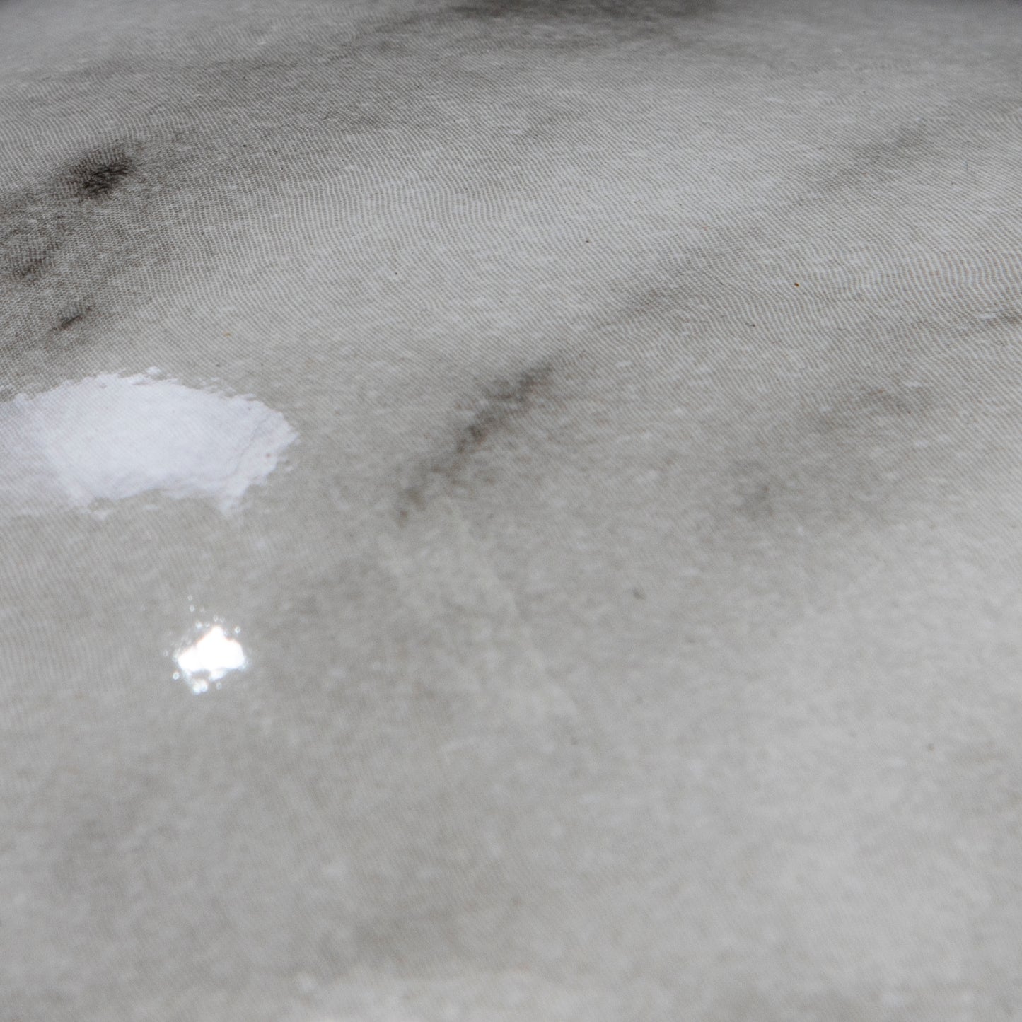 Closeup of grey textured fabric with subtle marblelike patterns and slight sheen