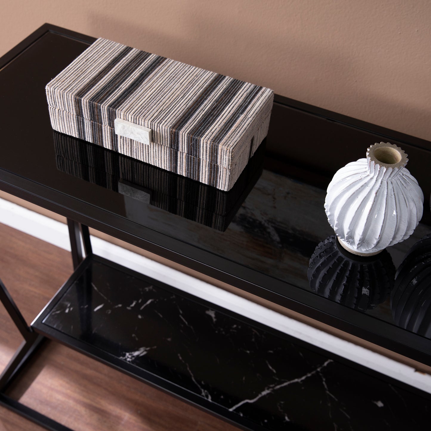 Striped rectangular storage box with white marble accent on a sleek black console table