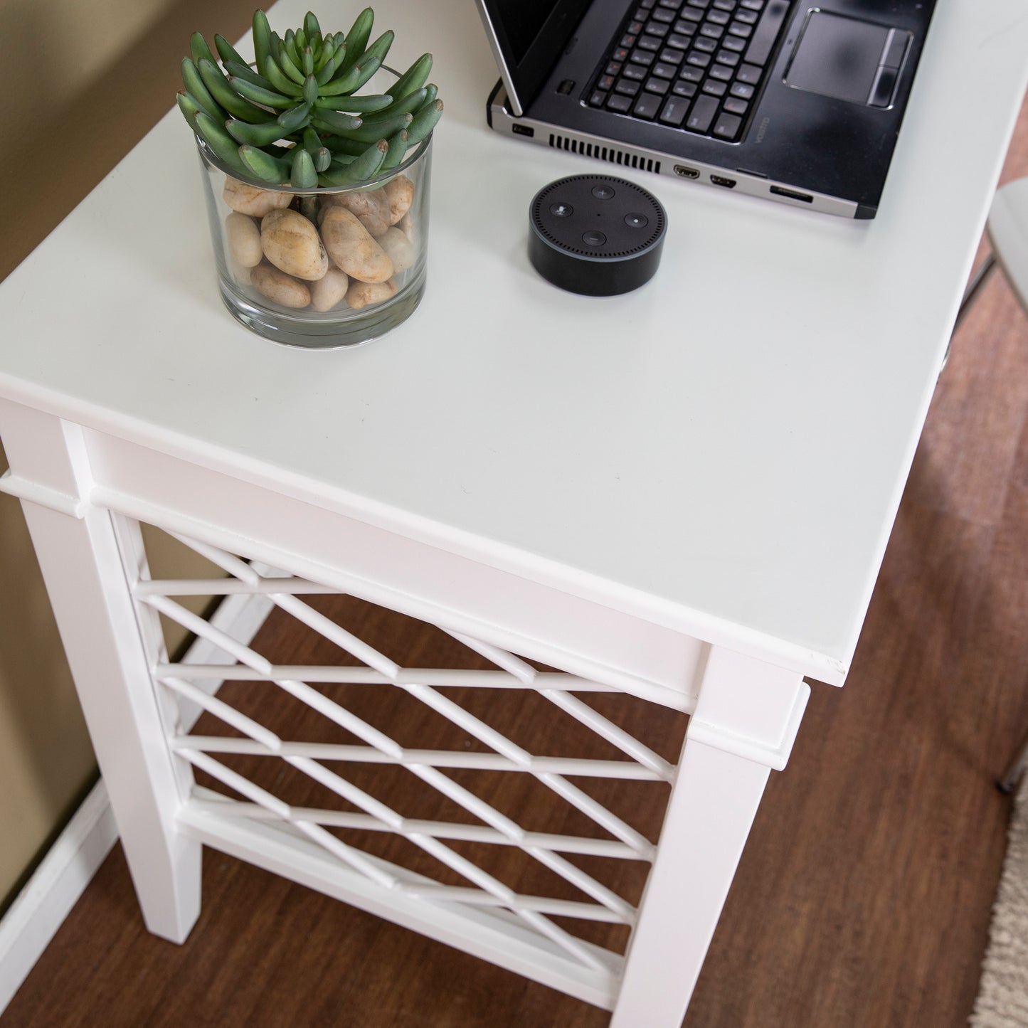 White end table with lattice side detail featuring a laptop and smart speaker