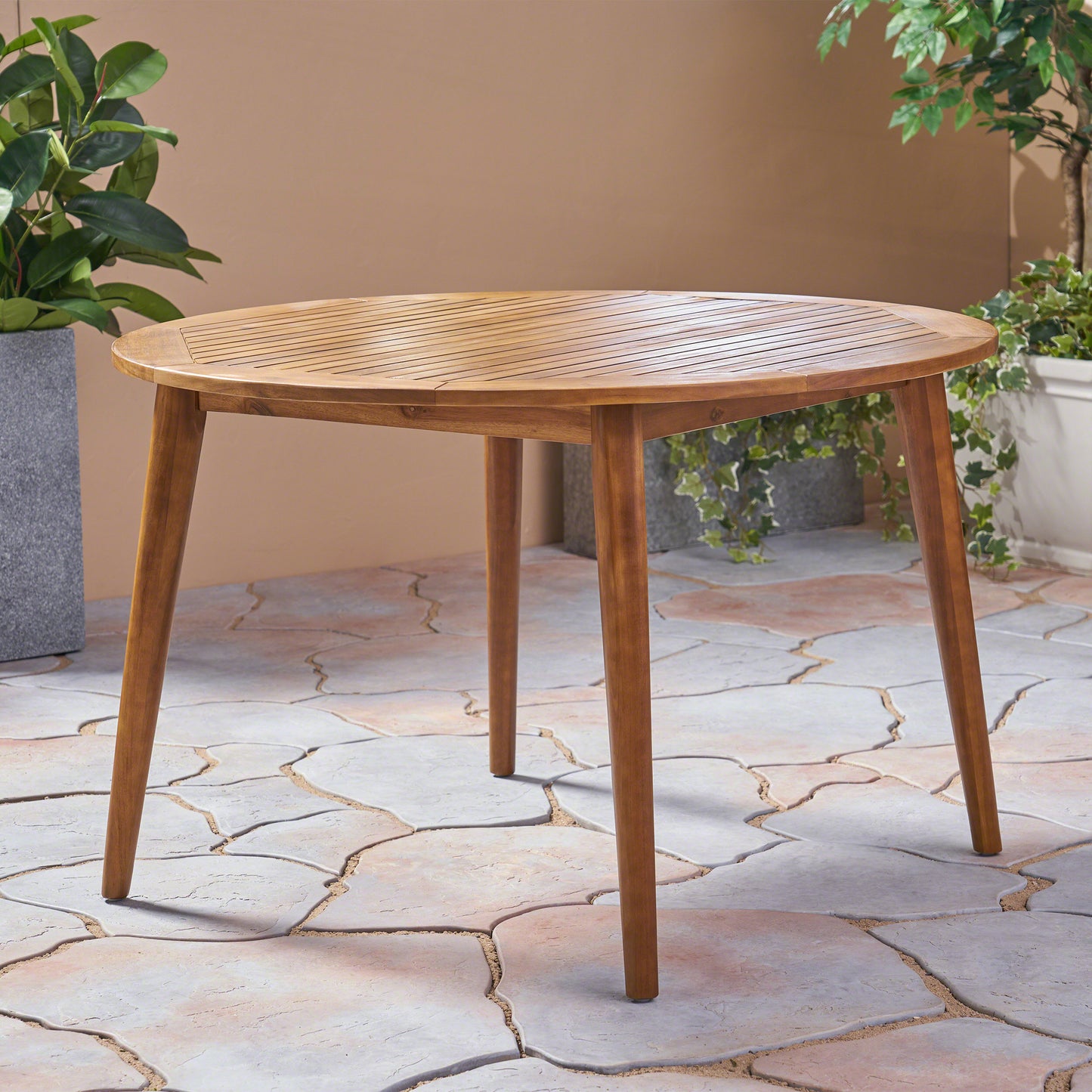 Round acacia wood patio dining table with slatted surface and tapered legs