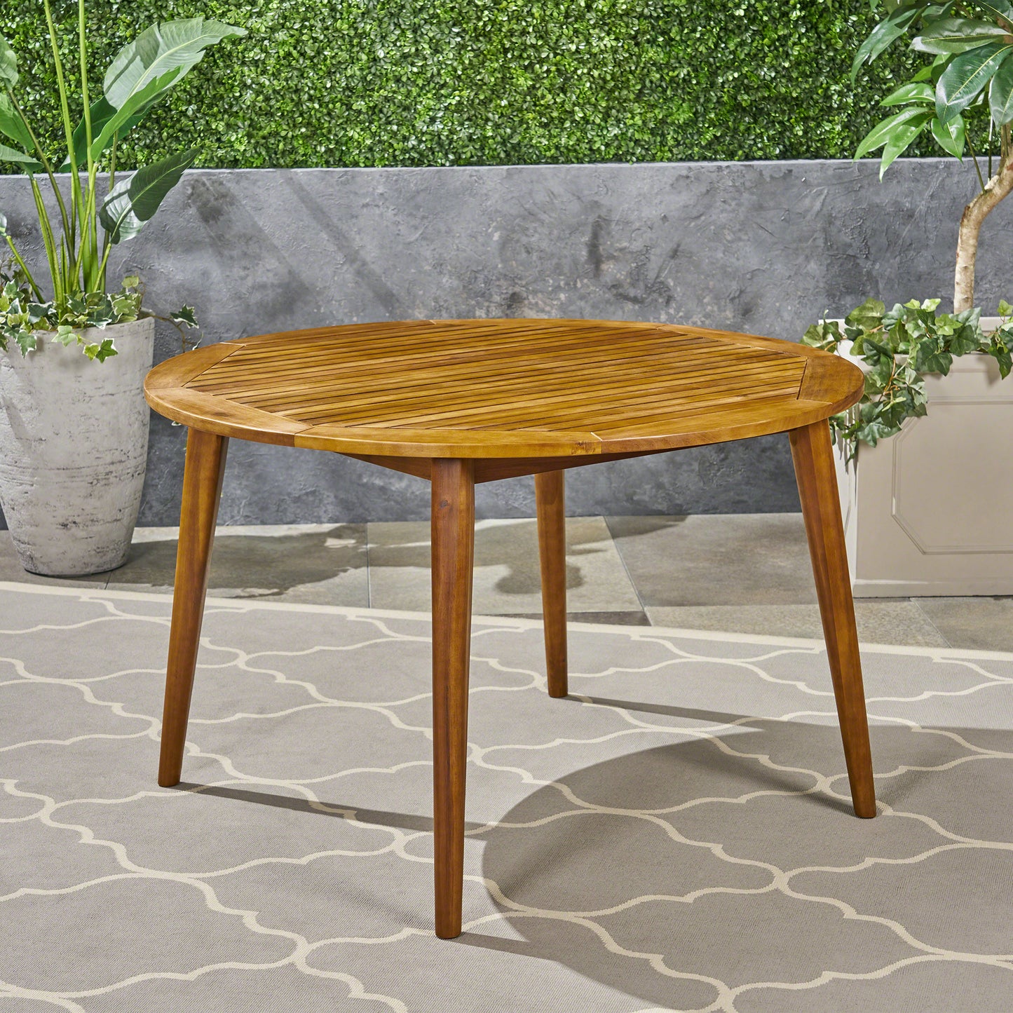 Round acacia wood dining table with slatted top and tapered legs perfect for patio use