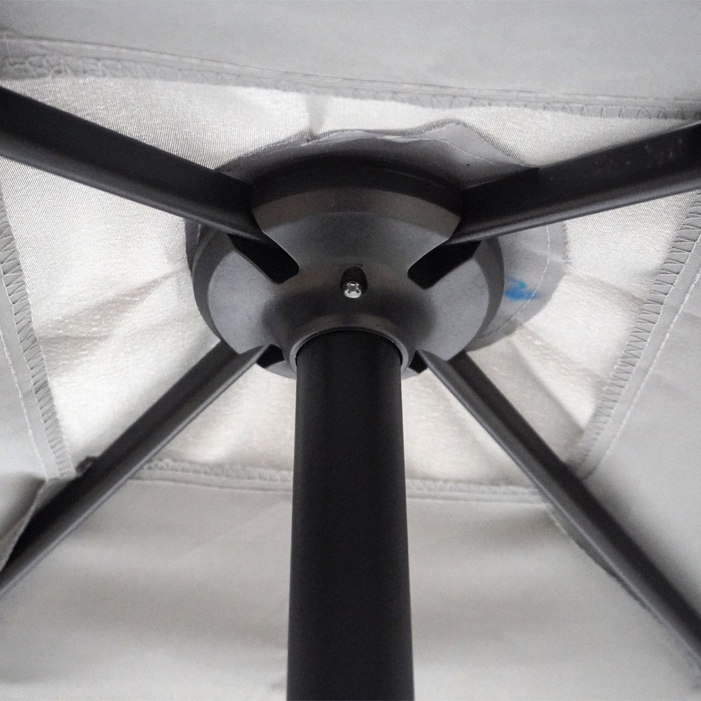 Closeup of black metal ribs and central pole of a gray patio umbrella showing construction details