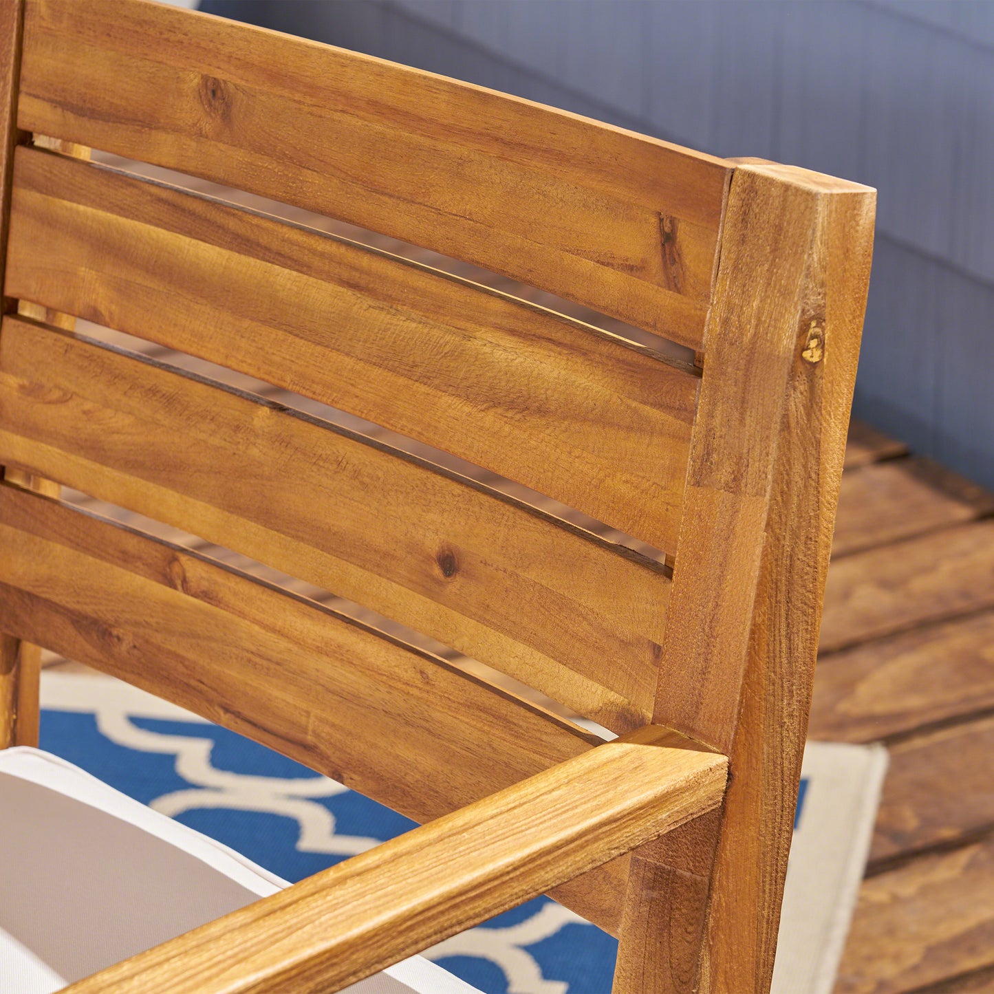 Closeup of natural acacia wood slats on an outdoor patio chair showing wood grain
