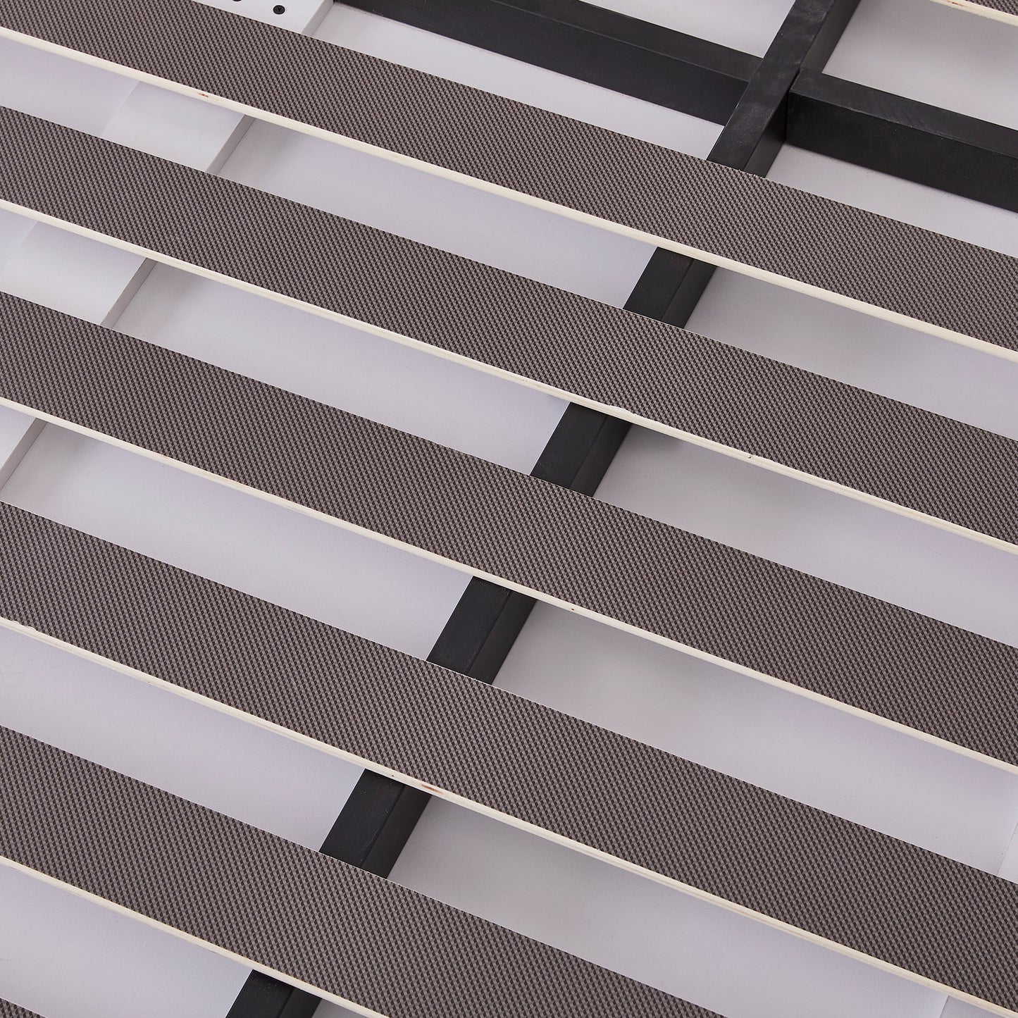 Closeup of a grey nonslip mattress support pad on a white bed frame