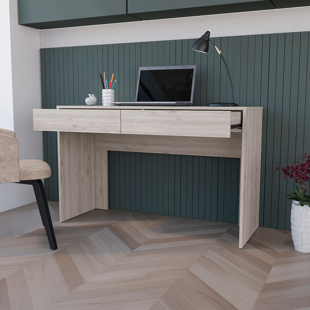 Light wood desk with two drawers a laptop and a black desk lamp