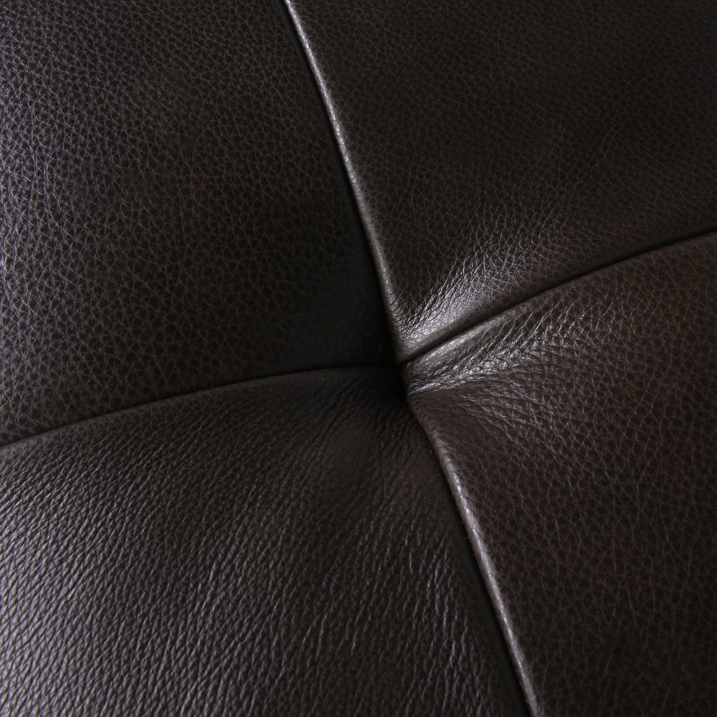 Closeup of rich dark brown leather with a subtle quilted pattern and visible grain