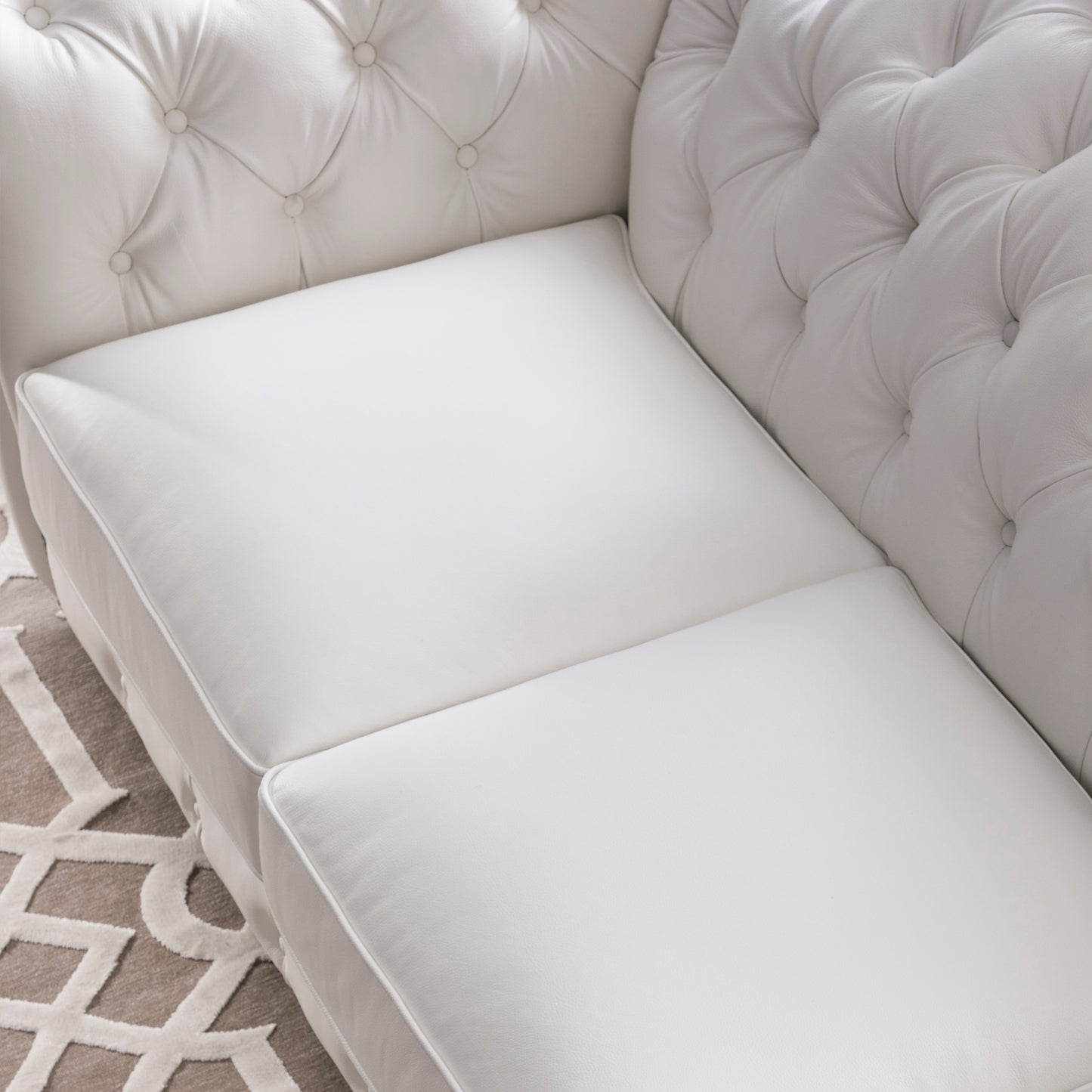 Closeup of a luxurious white leather sofa with tufted back cushions and plush seat