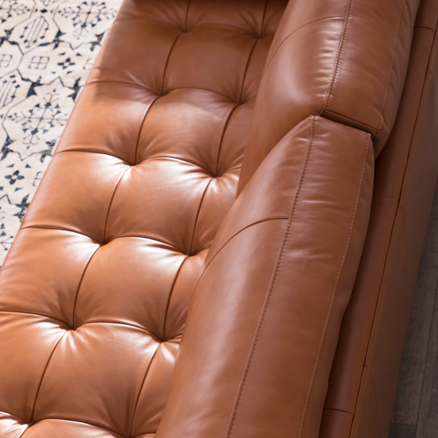 Closeup of tufted camel leather sofa armrest with detailed stitching