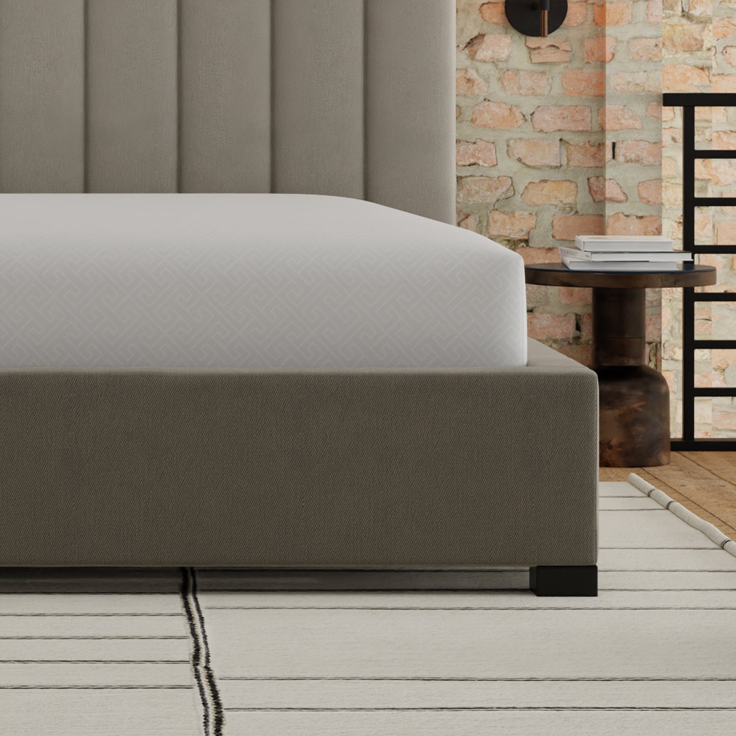 Tufted grey upholstered bed frame with a white geometric patterned fitted sheet