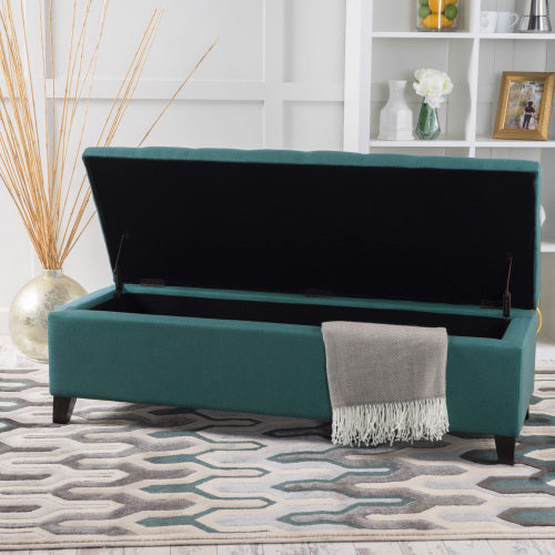 Teal storage bench with open lid tufted upholstery and a gray throw blanket