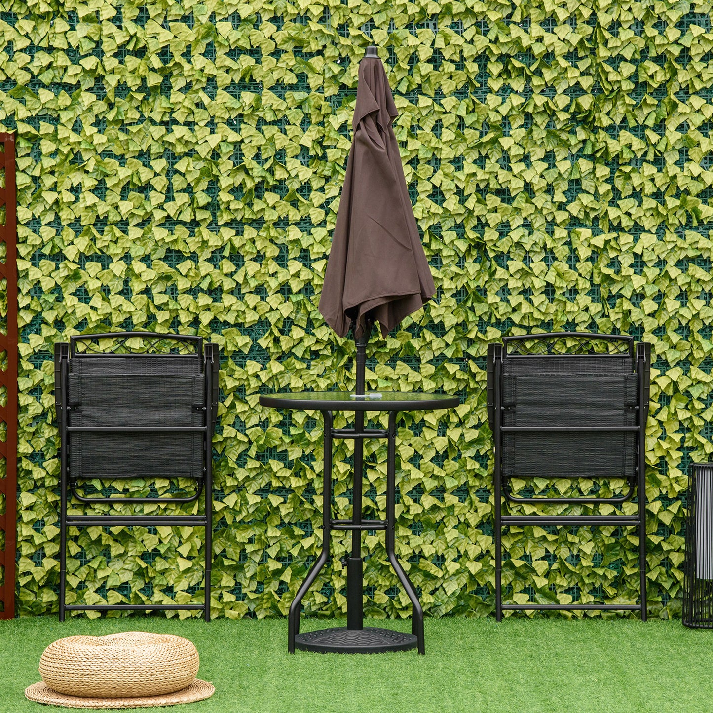 Two black folding patio chairs flank a small bistro table with a closed brown umbrella