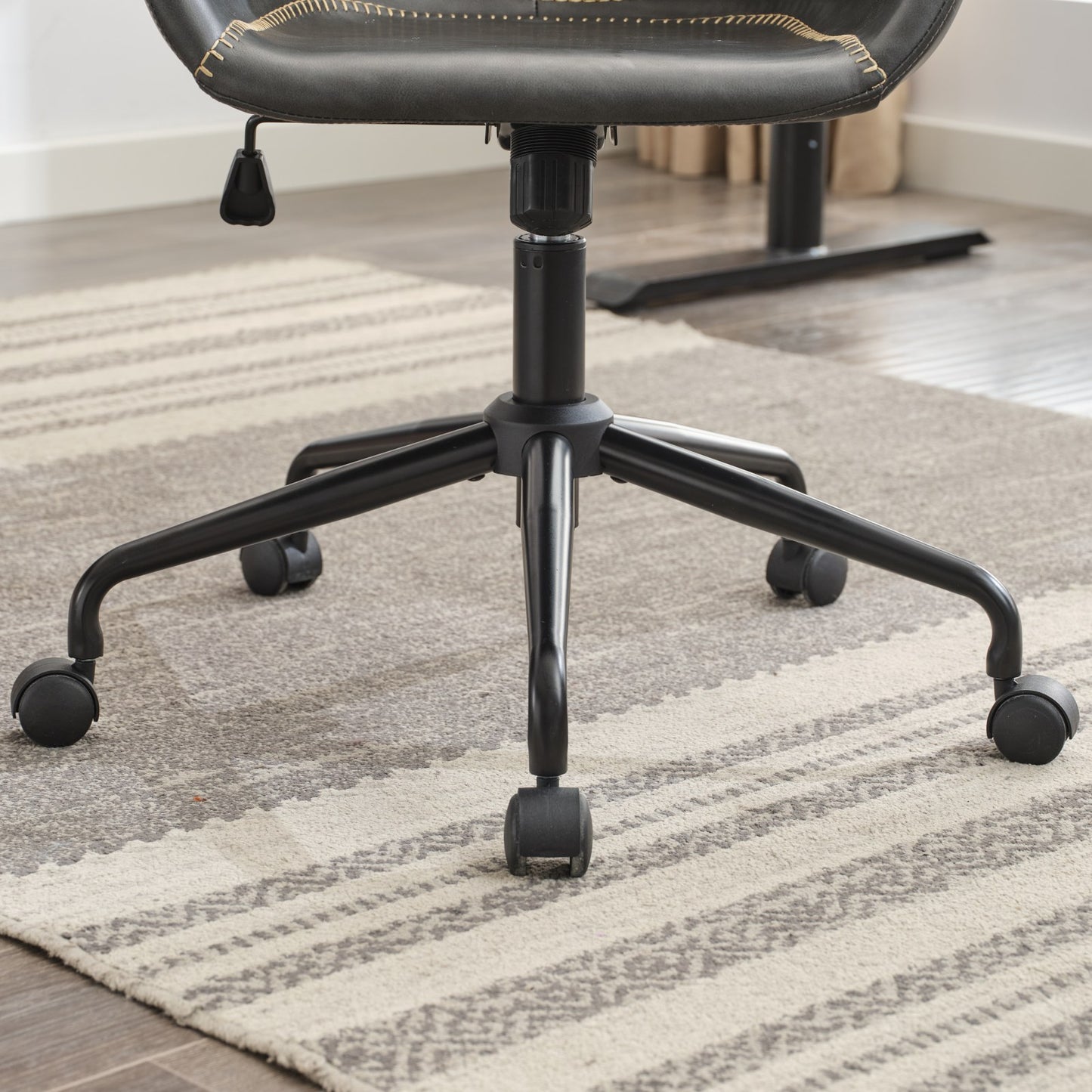 Black executive chair base with five rolling casters on striped carpet