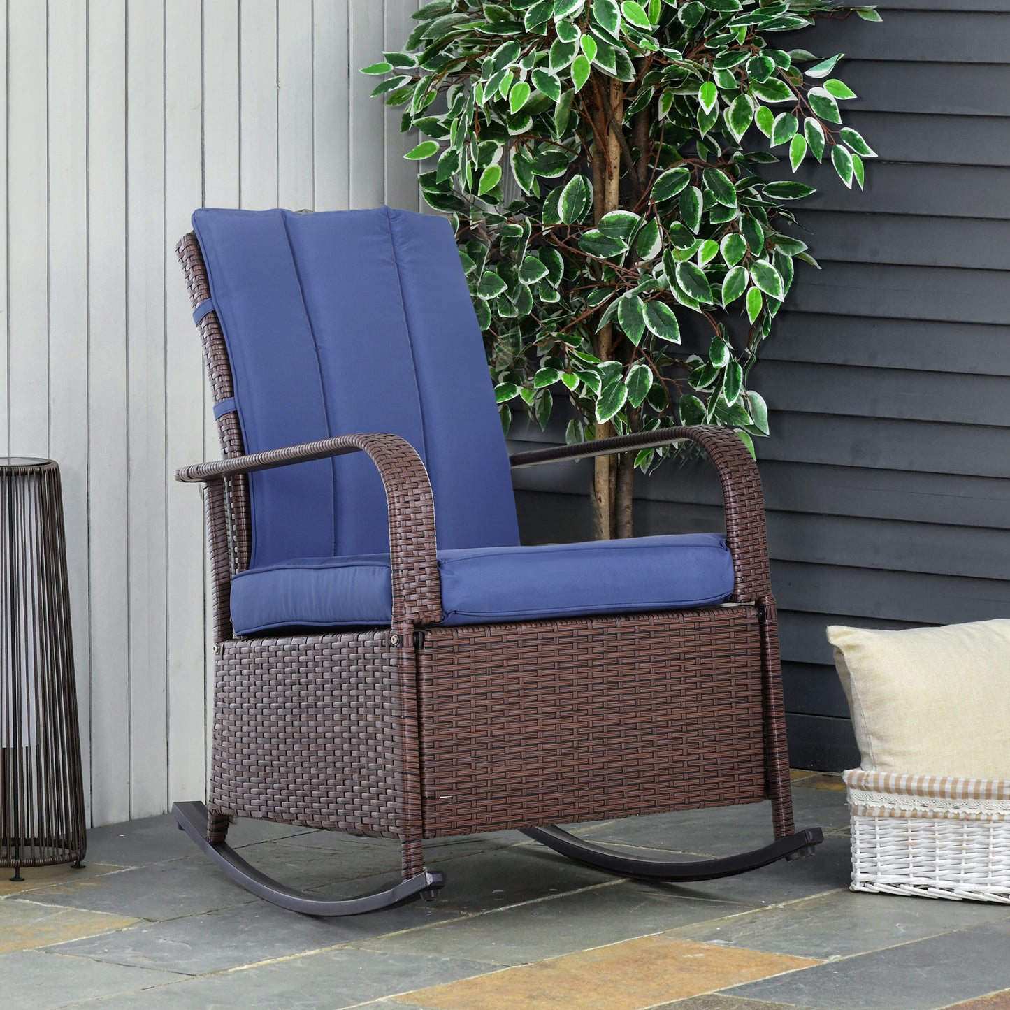 Brown rattan rocking chair with navy blue cushions on outdoor patio