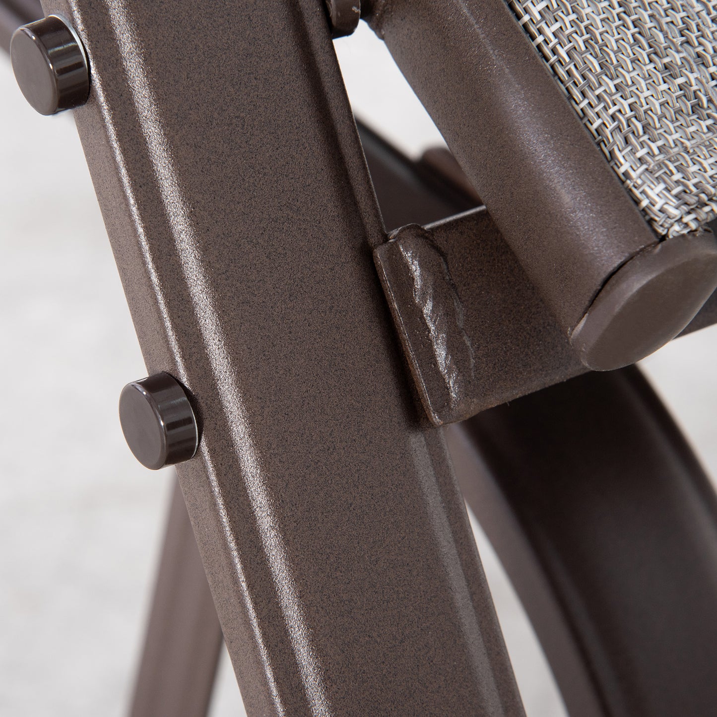 Closeup of a textured brown metal frame with a grey wicker seat detail on a patio chair