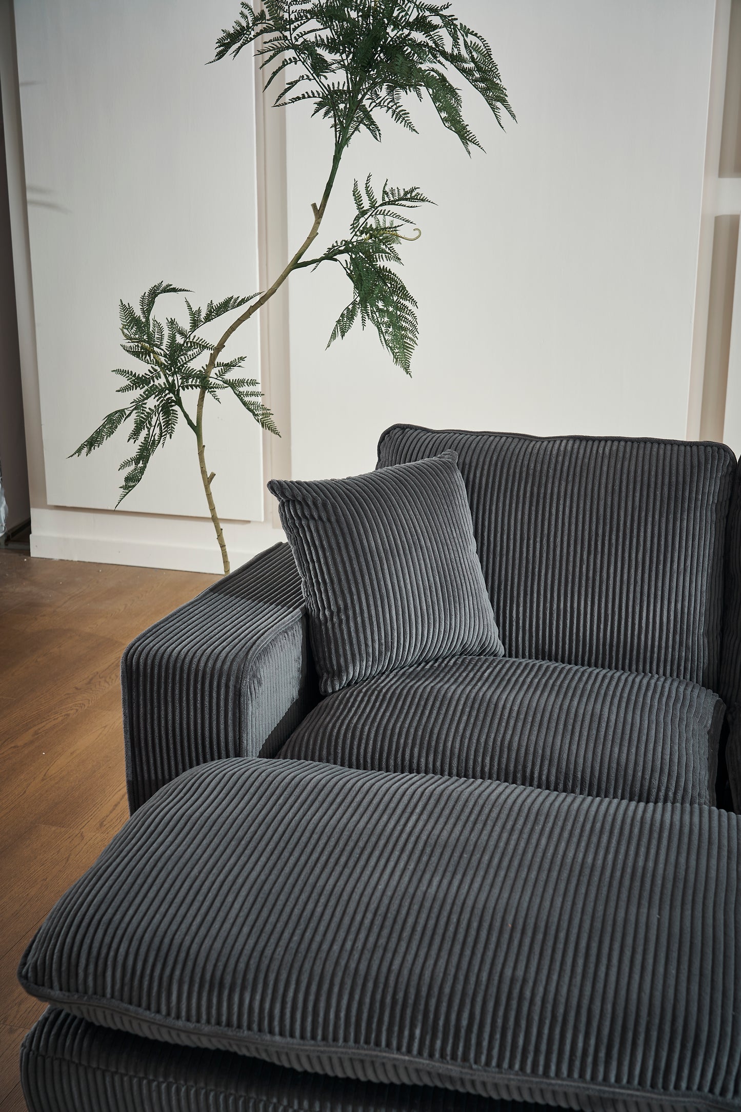 Dark grey corduroy sectional sofa with plush cushions and an ottoman perfect for modern living rooms