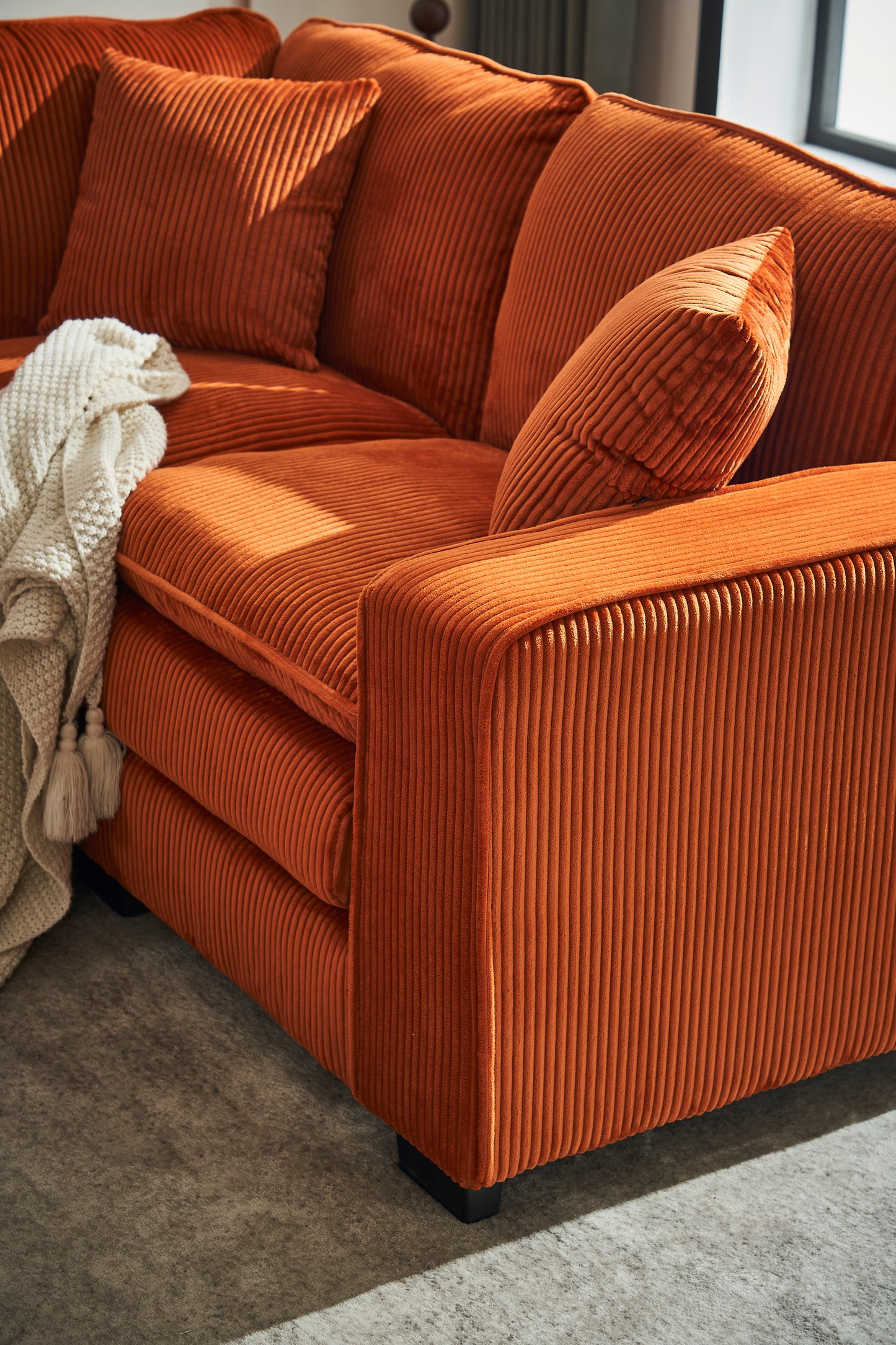 Orange corduroy sectional sofa with plush cushions and a cream throw blanket