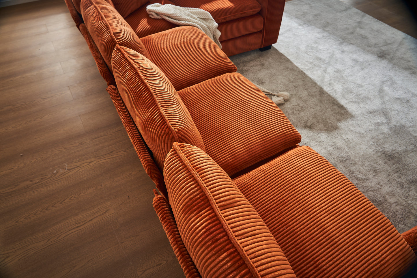 Orange corduroy sectional sofa with plush cushions and a textured finish