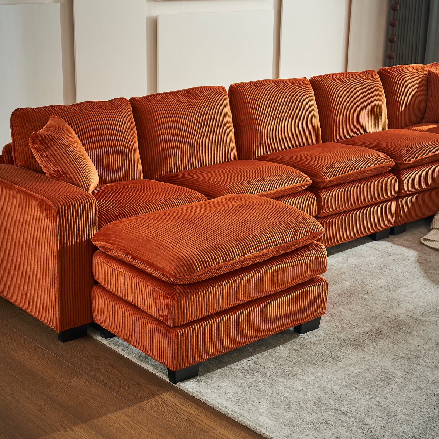 Orange corduroy sectional sofa with plush cushions and an ottoman