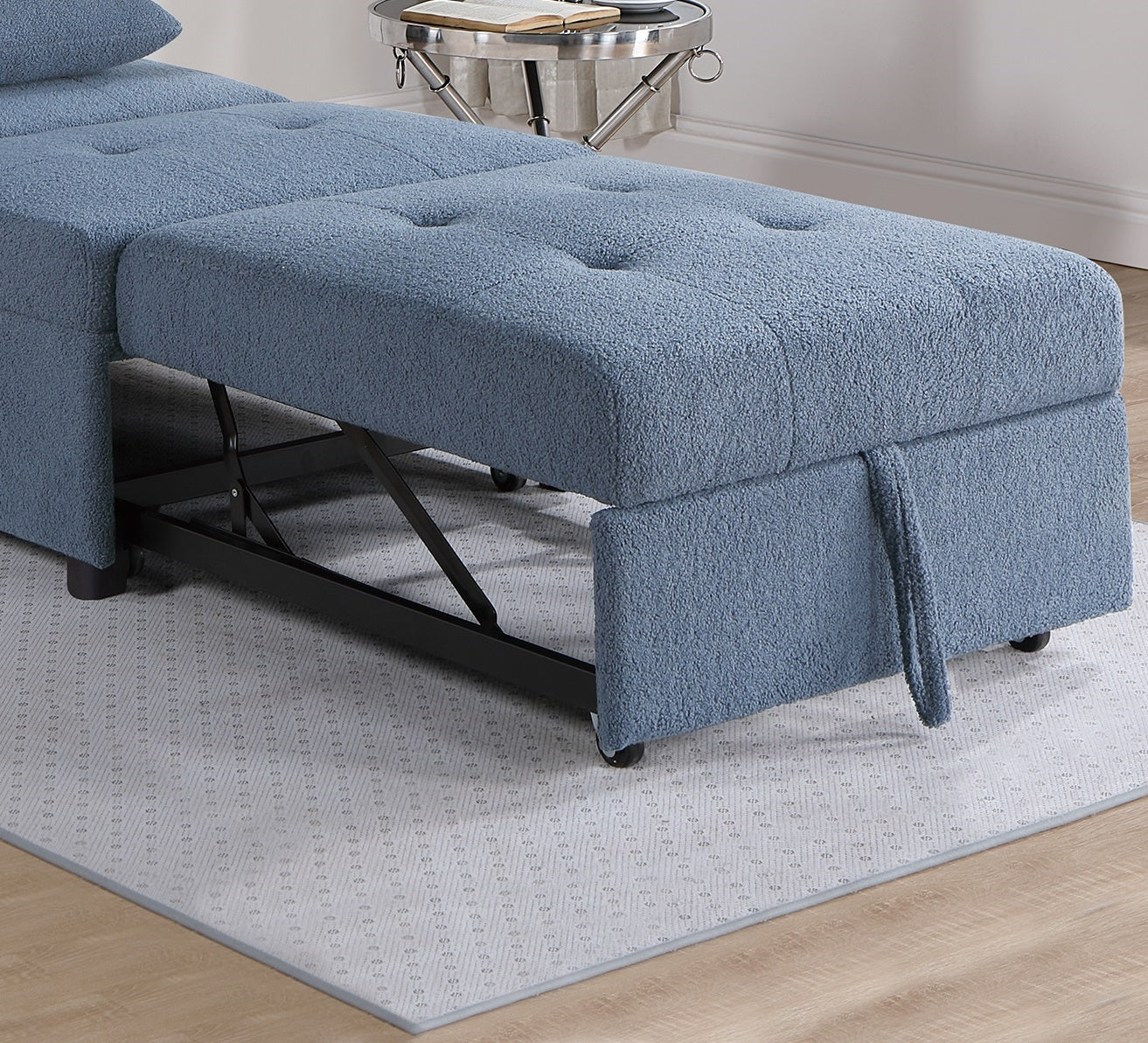 Blue fabric convertible sofa with tufted seat cushions and hidden rolling ottoman