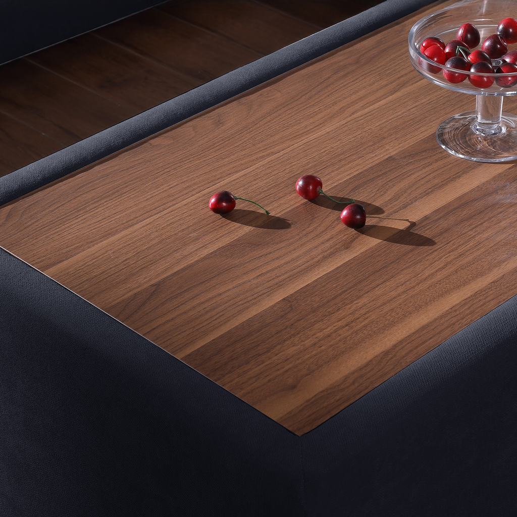 Walnut wood coffee table top with dark grey upholstered sides and fresh cherries