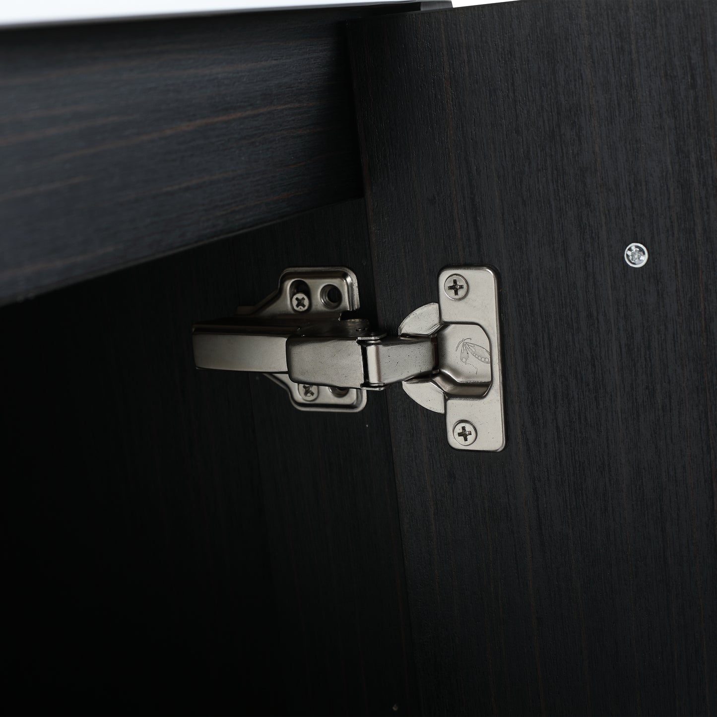 Closeup of brushed nickel cabinet hinge attached to dark wood door