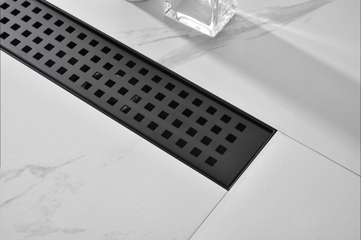 Sleek black linear shower drain with square perforations and a minimalist design