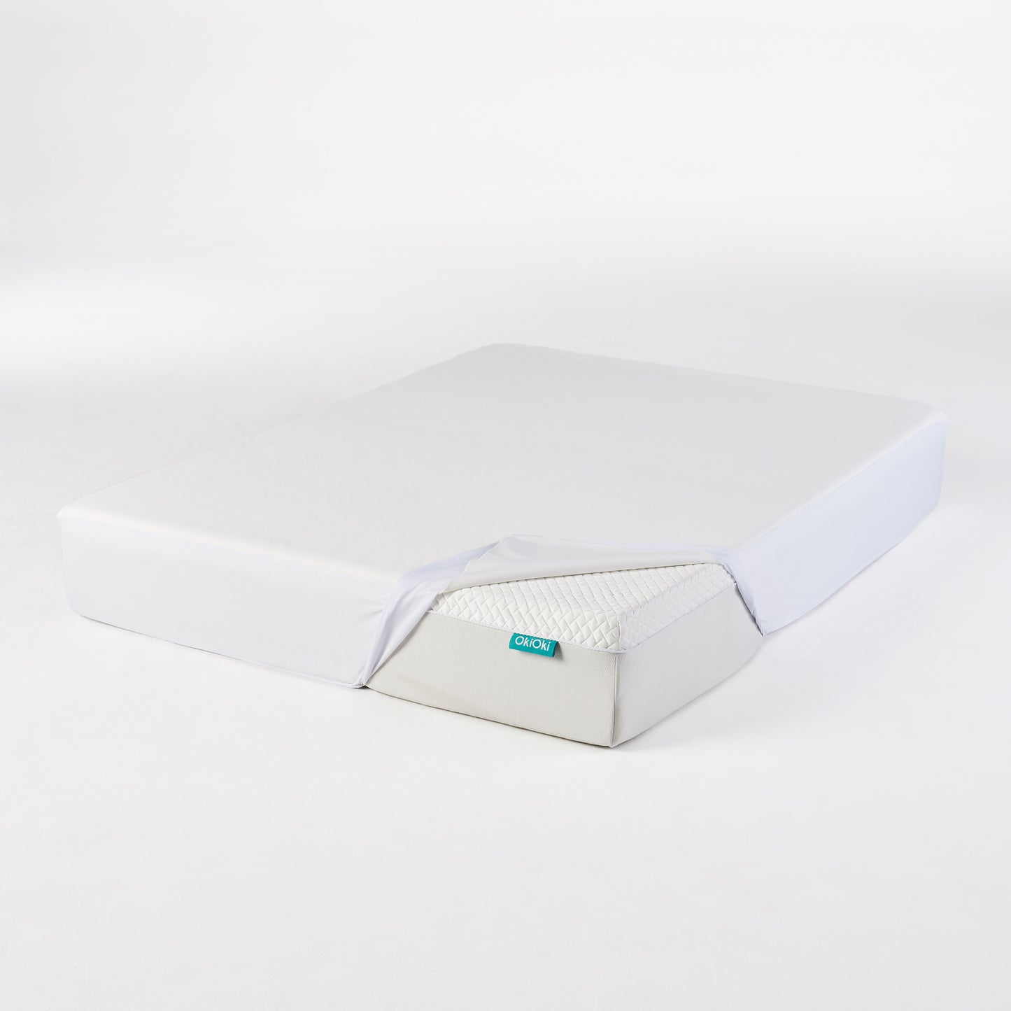 White OkiOki fitted sheet being placed on a mattress with quilted top