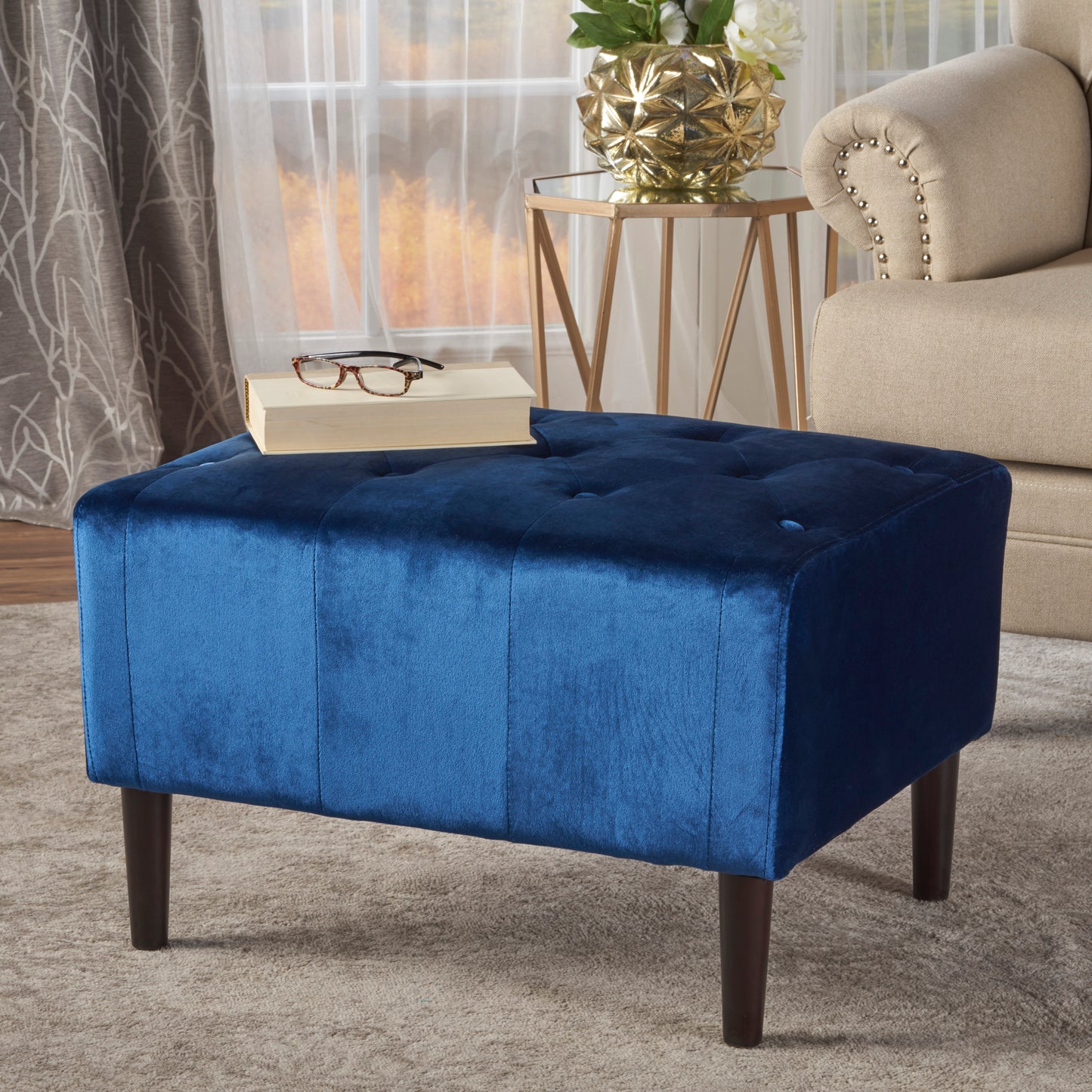 Deep blue velvet rectangular ottoman with button tufting and dark wood legs a chic accent piece