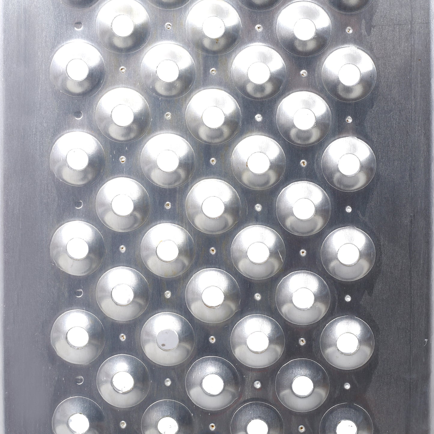Closeup of a shiny metal grater surface with circular grating holes for food preparation