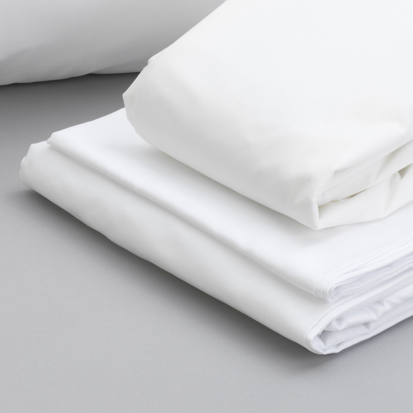 Crisp white cotton percale bed sheets folded neatly offering luxurious comfort and breathability for a restful night