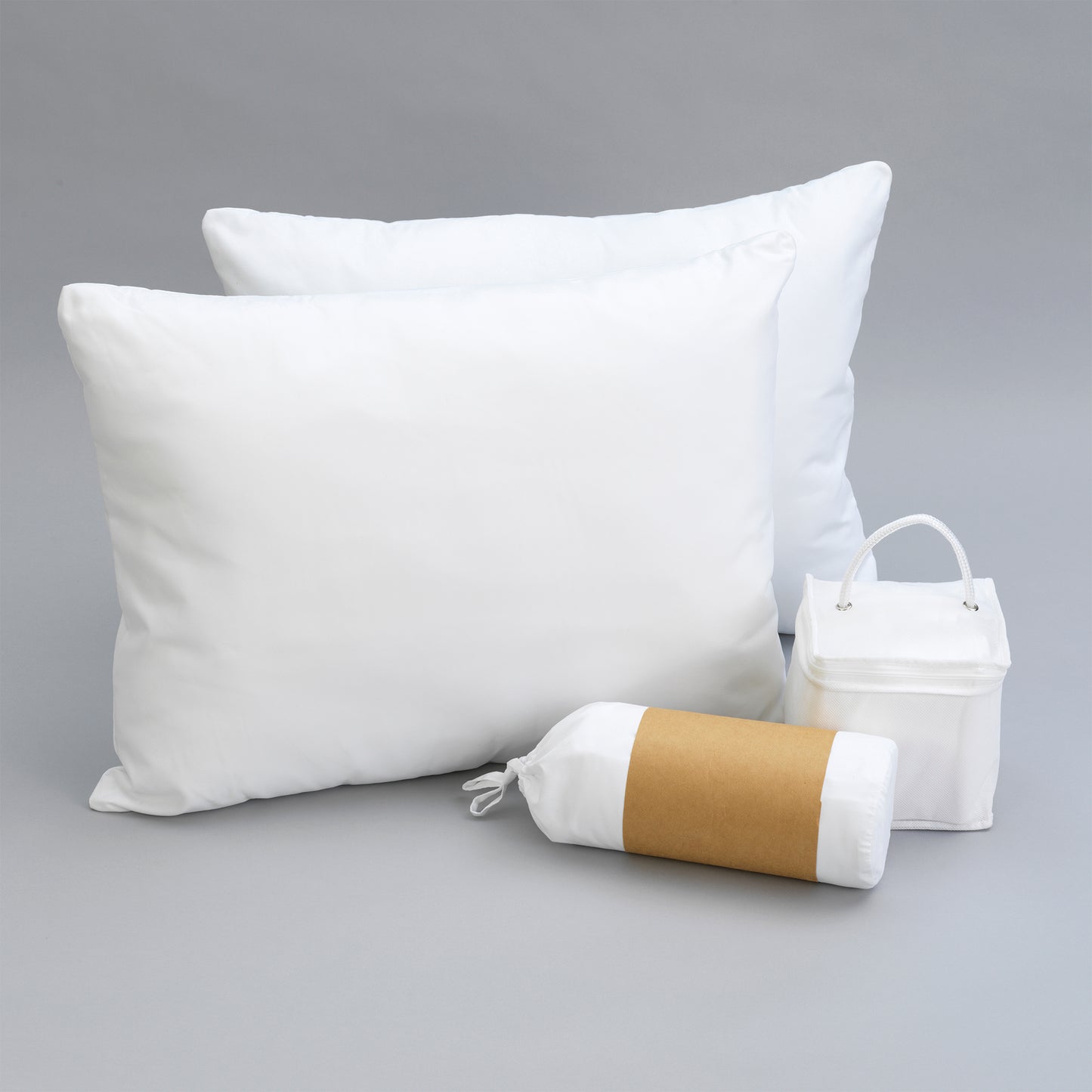 Two fluffy white down pillows with a storage bag and rolled pillow for travel