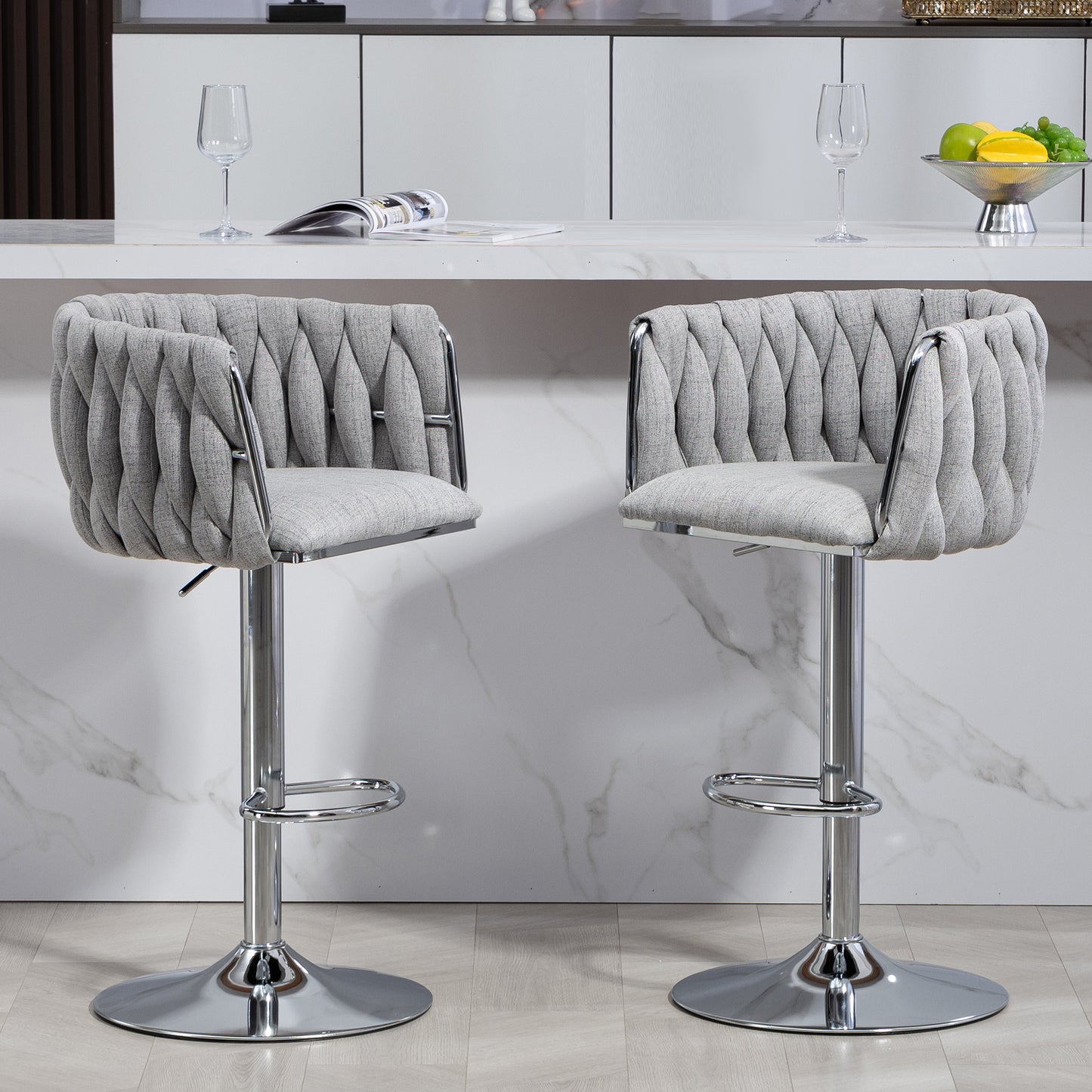 Two upholstered grey bar stools with chrome bases and adjustable height feature tufted backs