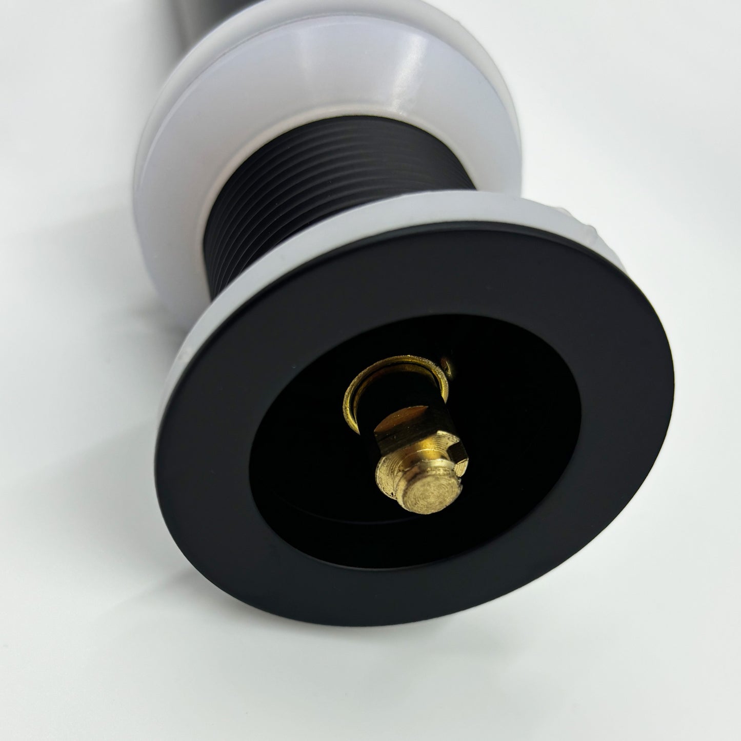 Black drain assembly with brass fitting and white cap detail for plumbing