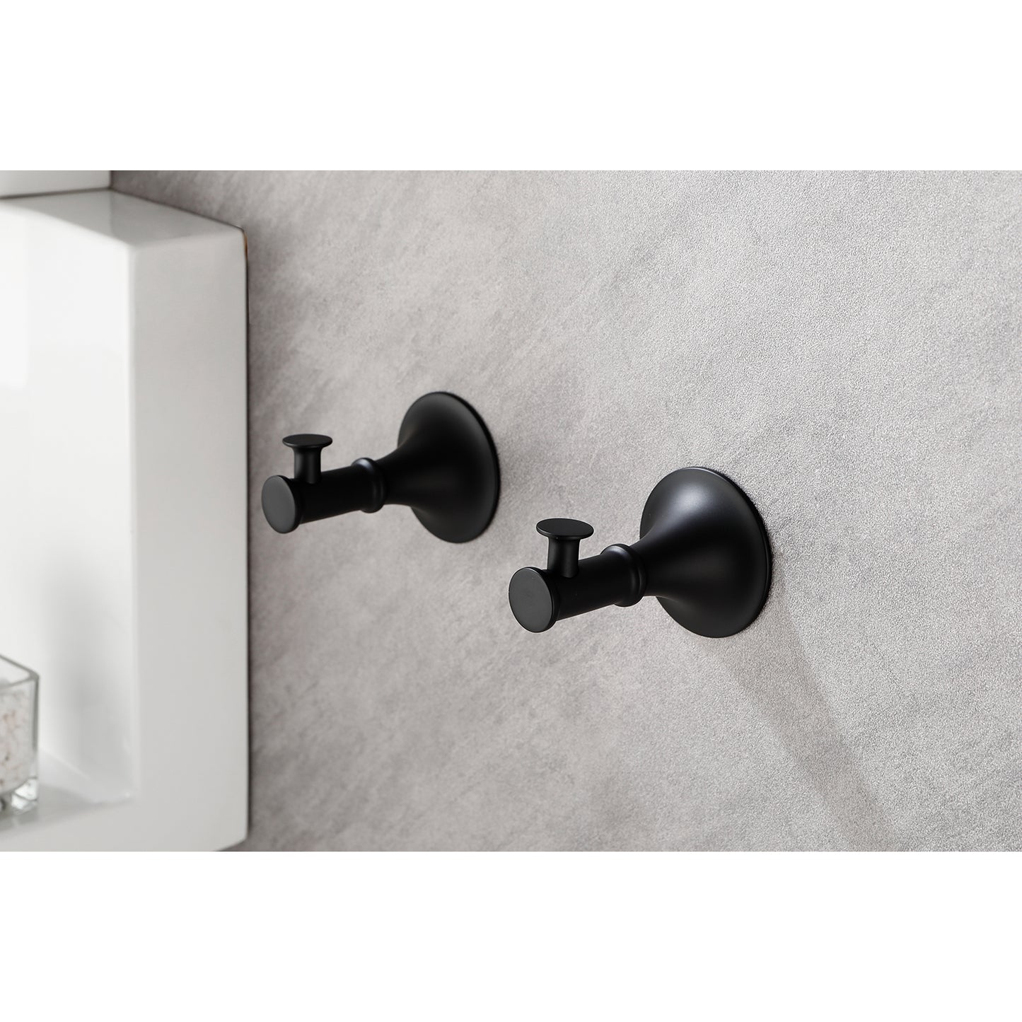 Two matte black wall hooks with minimalist design mounted on a grey textured wall