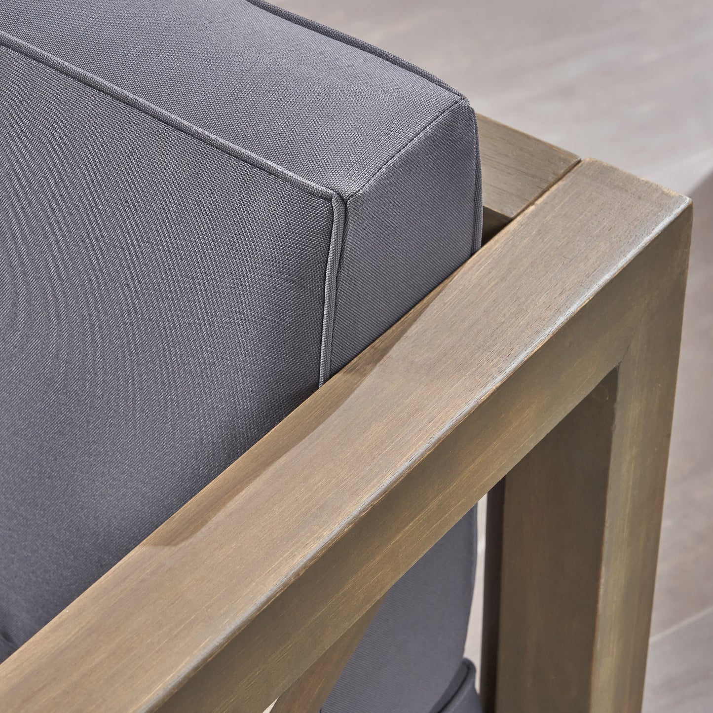 Closeup of a grey outdoor armchair cushion with a wooden frame detail